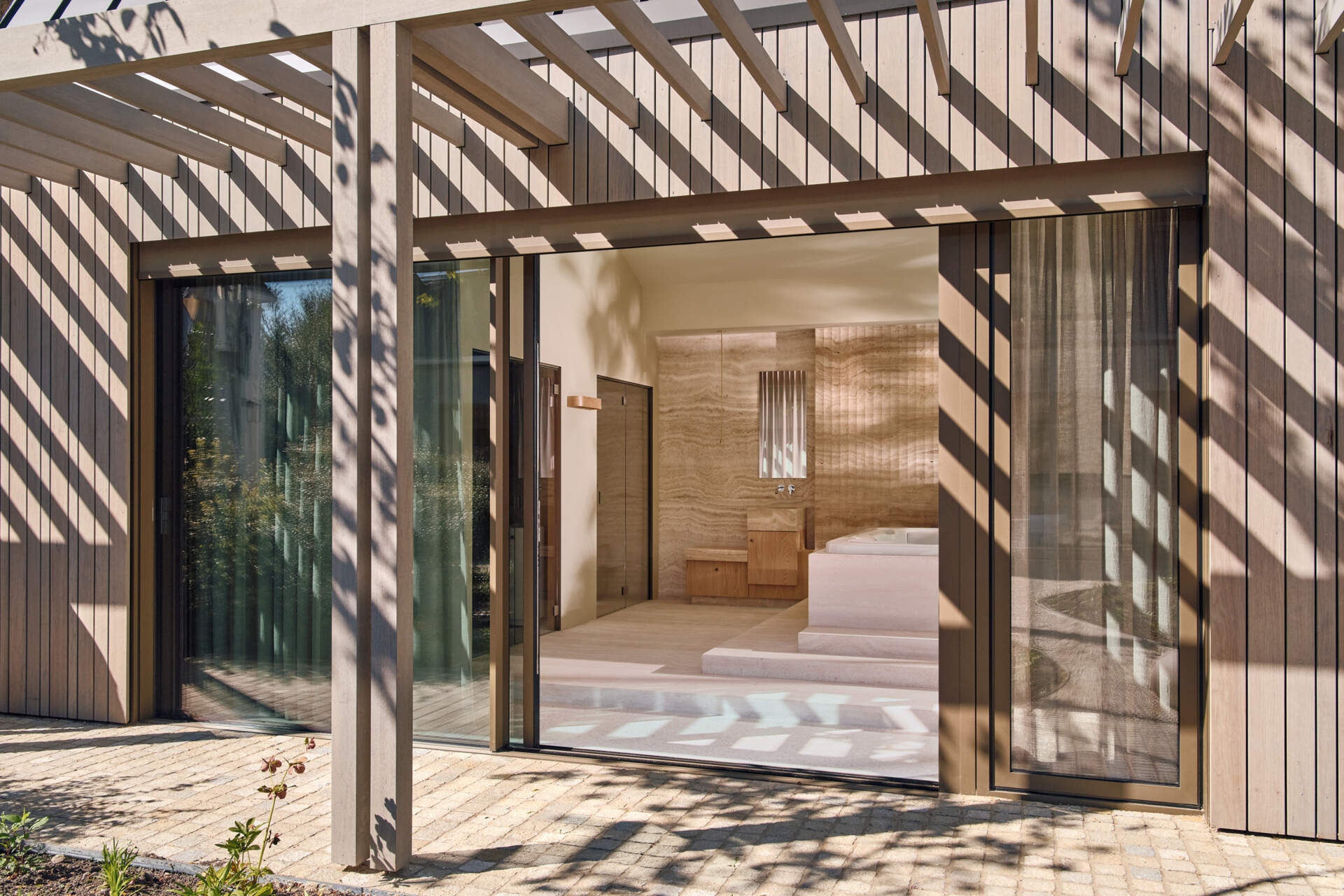 Travertine walls, a garden-facing jacuzzi, and sculptural lounge furniture turn this wellness wing into a luxurious escape at home.