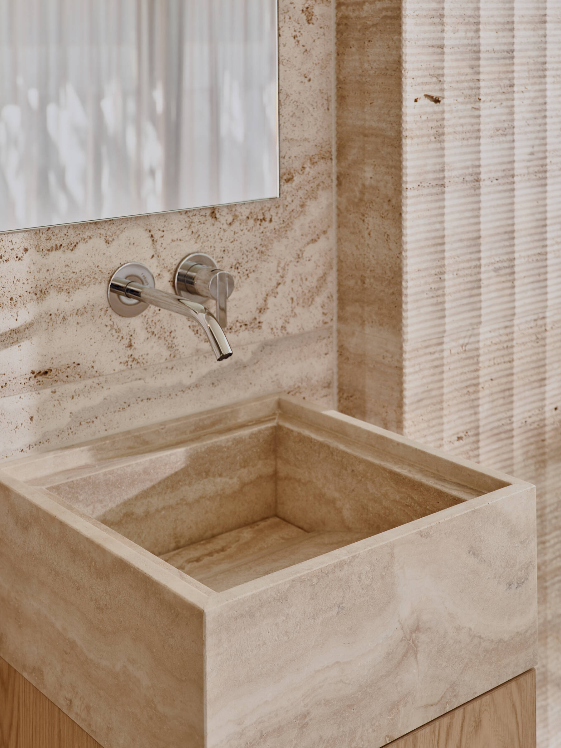 Travertine walls, a garden-facing jacuzzi, and sculptural lounge furniture turn this wellness wing into a luxurious escape at home.