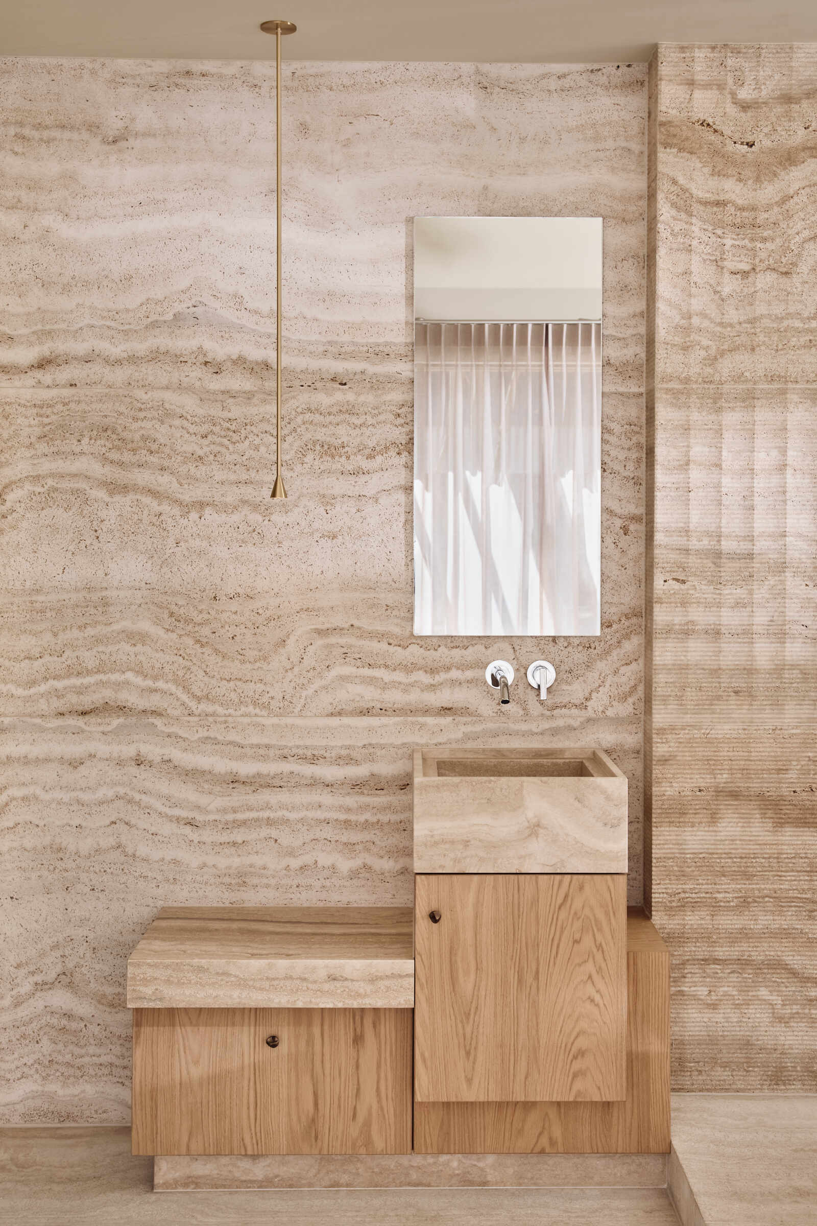 Travertine walls, a garden-facing jacuzzi, and sculptural lounge furniture turn this wellness wing into a luxurious escape at home.