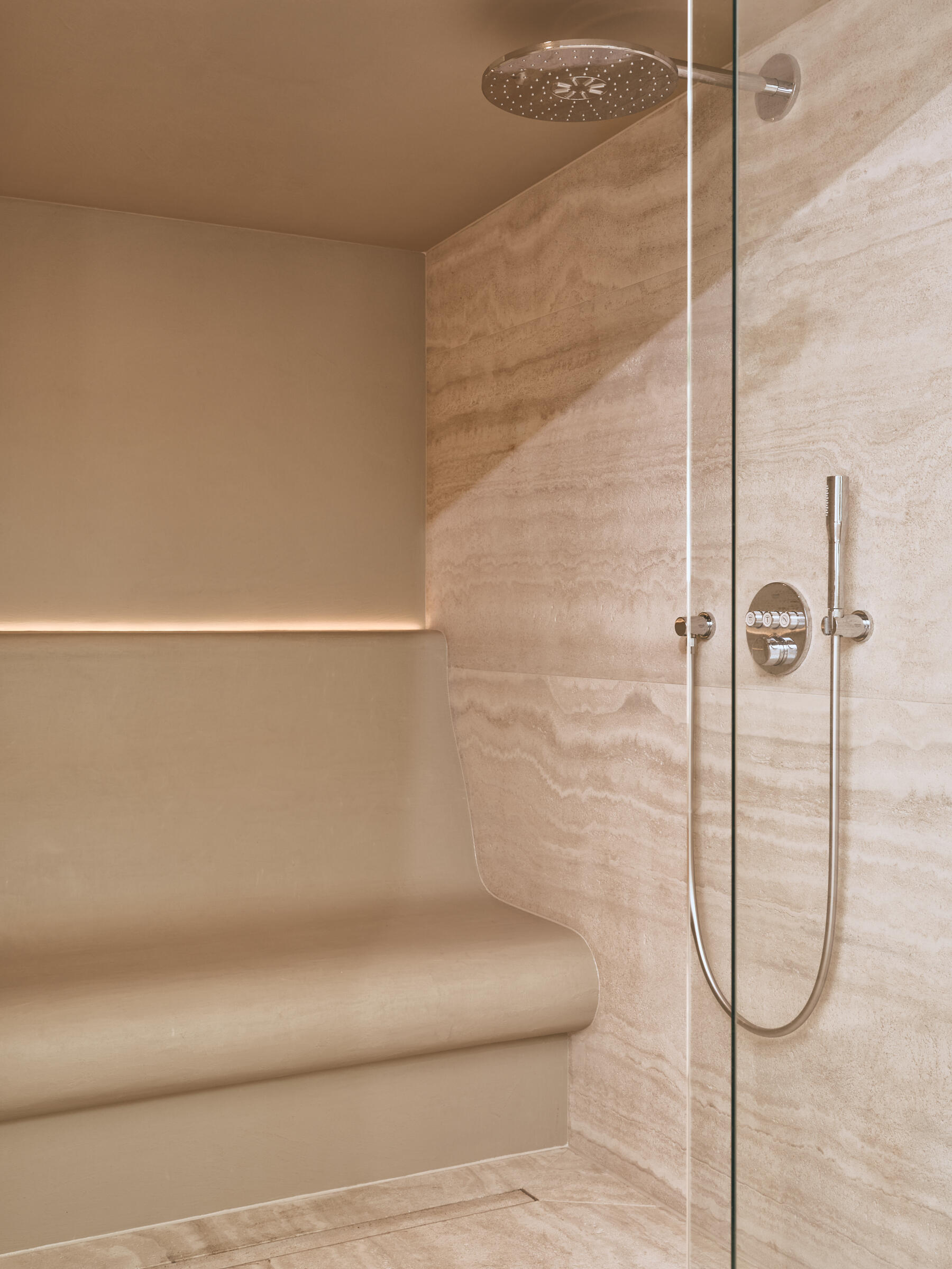 Travertine walls, a garden-facing jacuzzi, and sculptural lounge furniture turn this wellness wing into a luxurious escape at home.