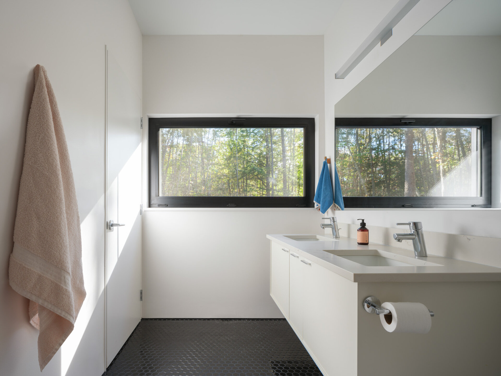 Natural light plays an important role in the bathroom, helping even smaller spaces feel open and airy. The simplicity of the bathroom with its white vanity and black tiles allows the room stand out without excessive decoration or visual clutter.