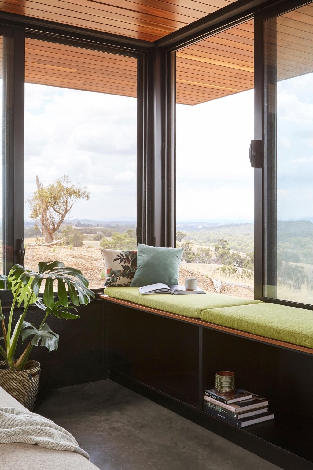 A minimalist bedroom with a large picture window framing expansive countryside views.