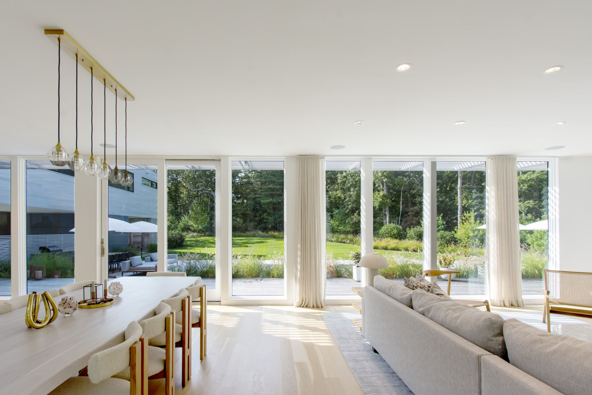 Natural light, forest views, and direct access to outdoor terraces define this bright contemporary dining space.