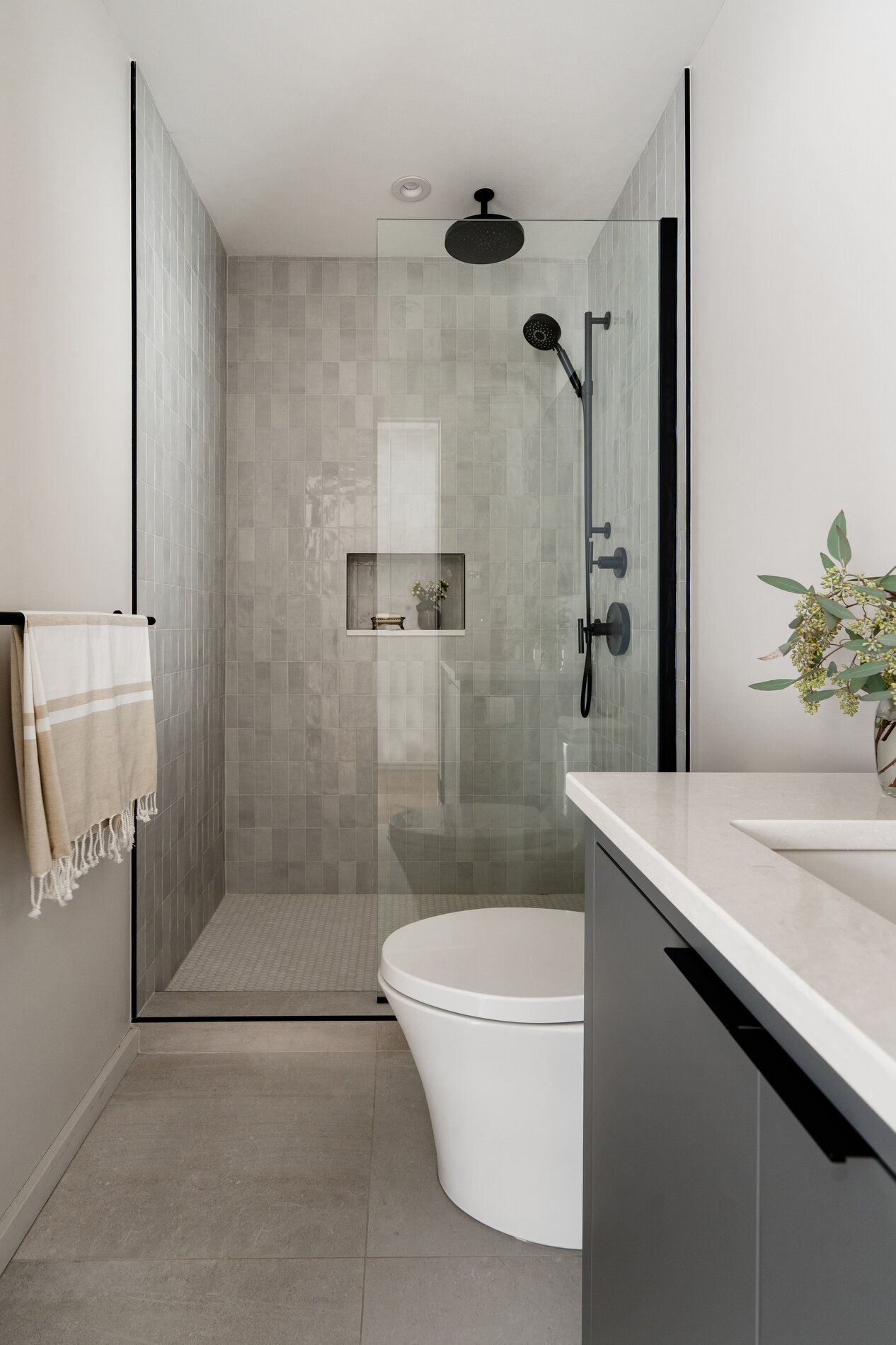 A modern bathroom with a built-in shelving niche in the shower.