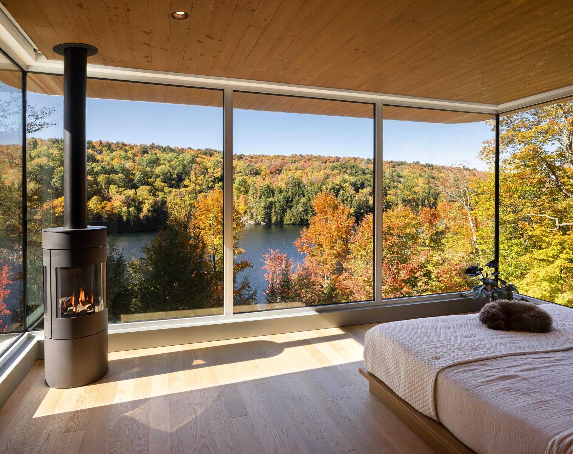 Positioned like a suspended volume above the landscape, the primary quarters include a bedroom, bathroom, office, meditation room, and walk-in closet. Large windows keep the scenery constantly present, while the warm wood palette adds softness and comfort.