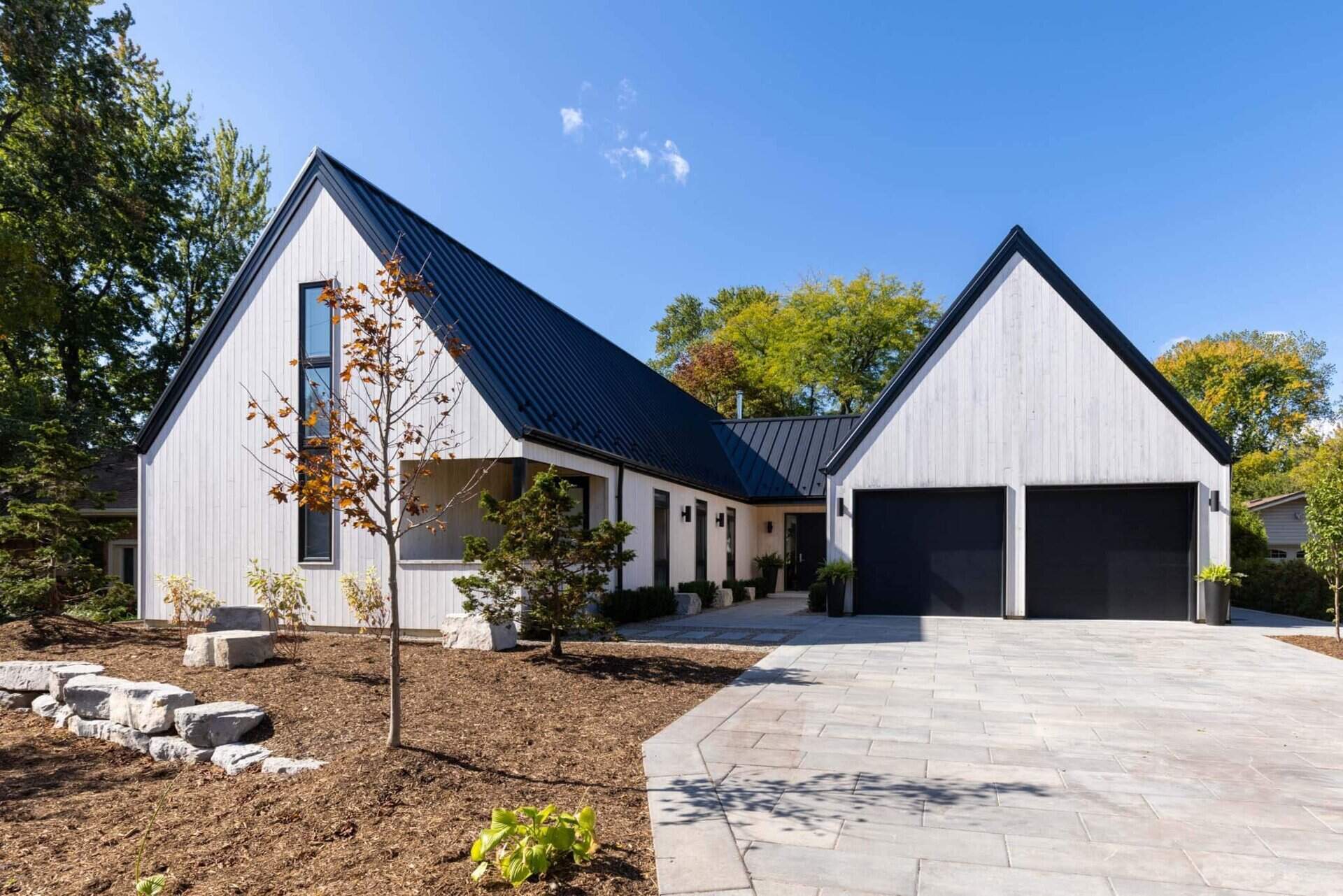 A modern Scandinavian-inspired home in Windsor, Ontario uses three clean-lined volumes to organize living, sleeping, and garage spaces into a striking J-shaped layout.