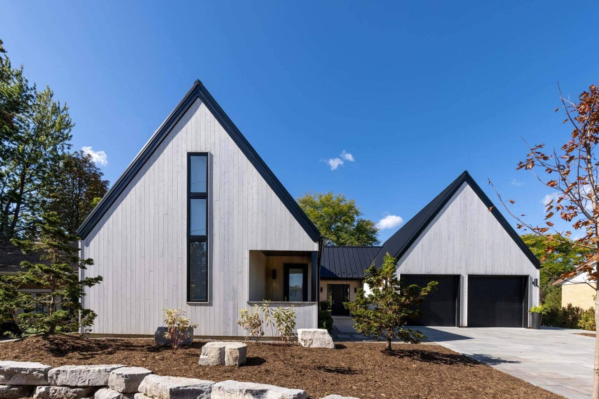 A modern Scandinavian-inspired home in Windsor, Ontario uses three clean-lined volumes to organize living, sleeping, and garage spaces into a striking J-shaped layout.