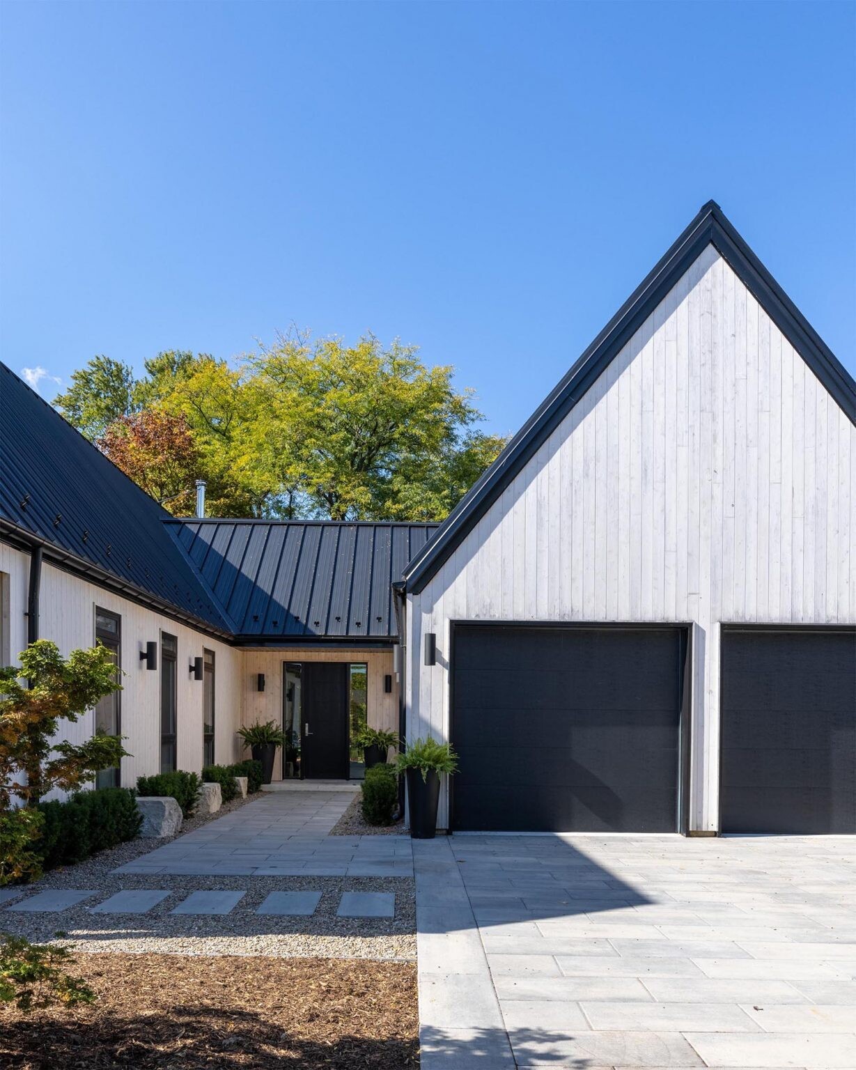 Vertical white cedar siding and black standing seam roofs give this Scandinavian-inspired Windsor home a bold modern exterior with warm natural texture.