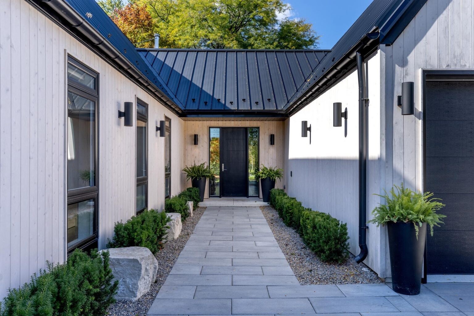 Vertical white cedar siding and black standing seam roofs give this Scandinavian-inspired Windsor home a bold modern exterior with warm natural texture.