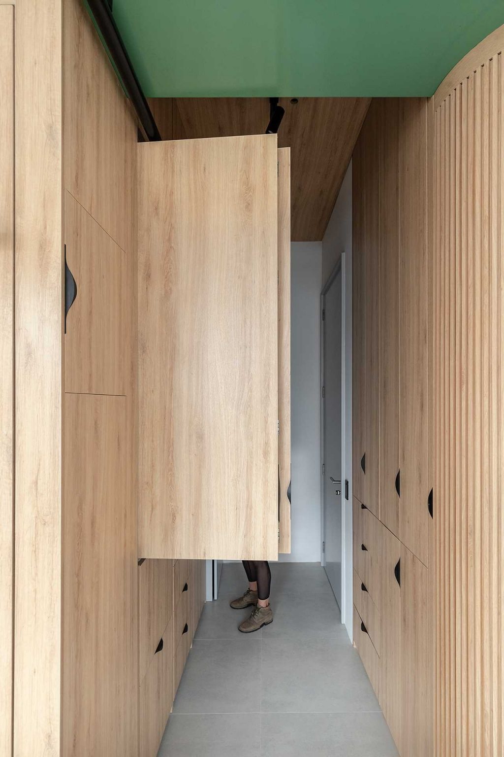 Hidden behind folding cabinet doors, this compact kitchen combines warm wood finishes with dark countertops to create a sleek and functional cooking space.