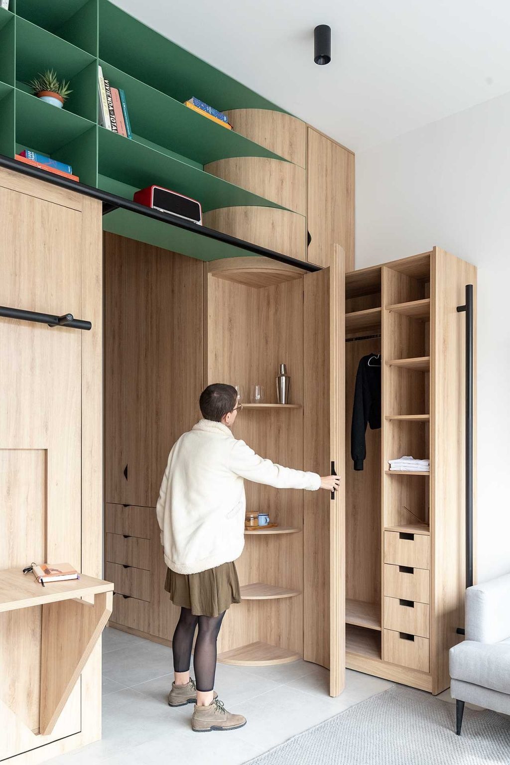 A curved wood cabinet softens the interior while providing extra shelving, adding warmth and sculptural appeal to this compact apartment.