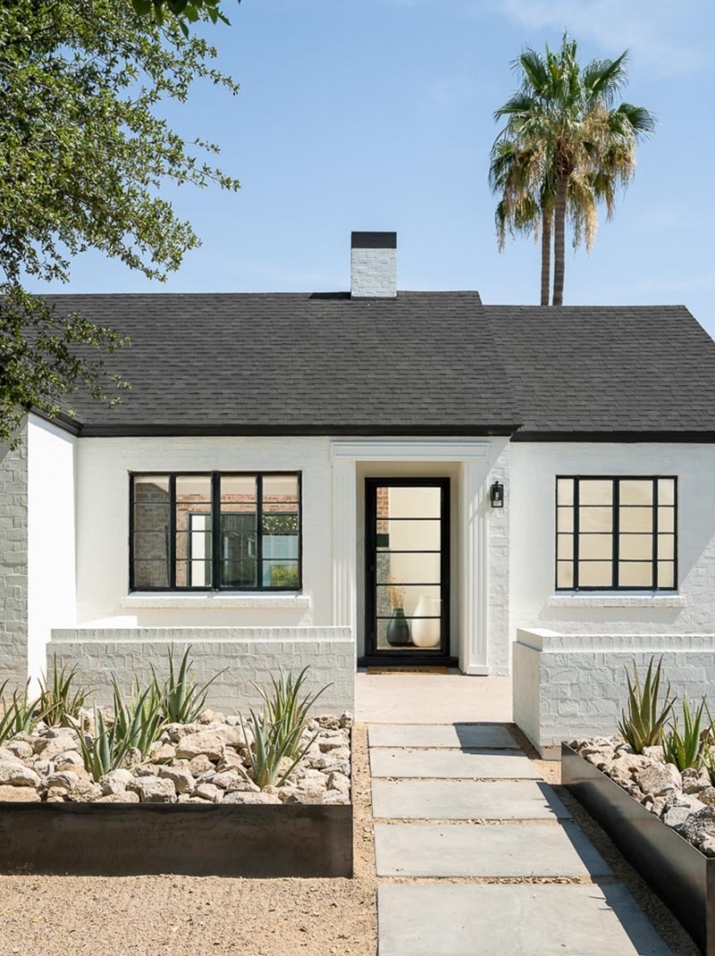 This Phoenix remodel pairs a white historic exterior with a bold black standing seam metal addition, large picture windows, and modern desert landscaping.