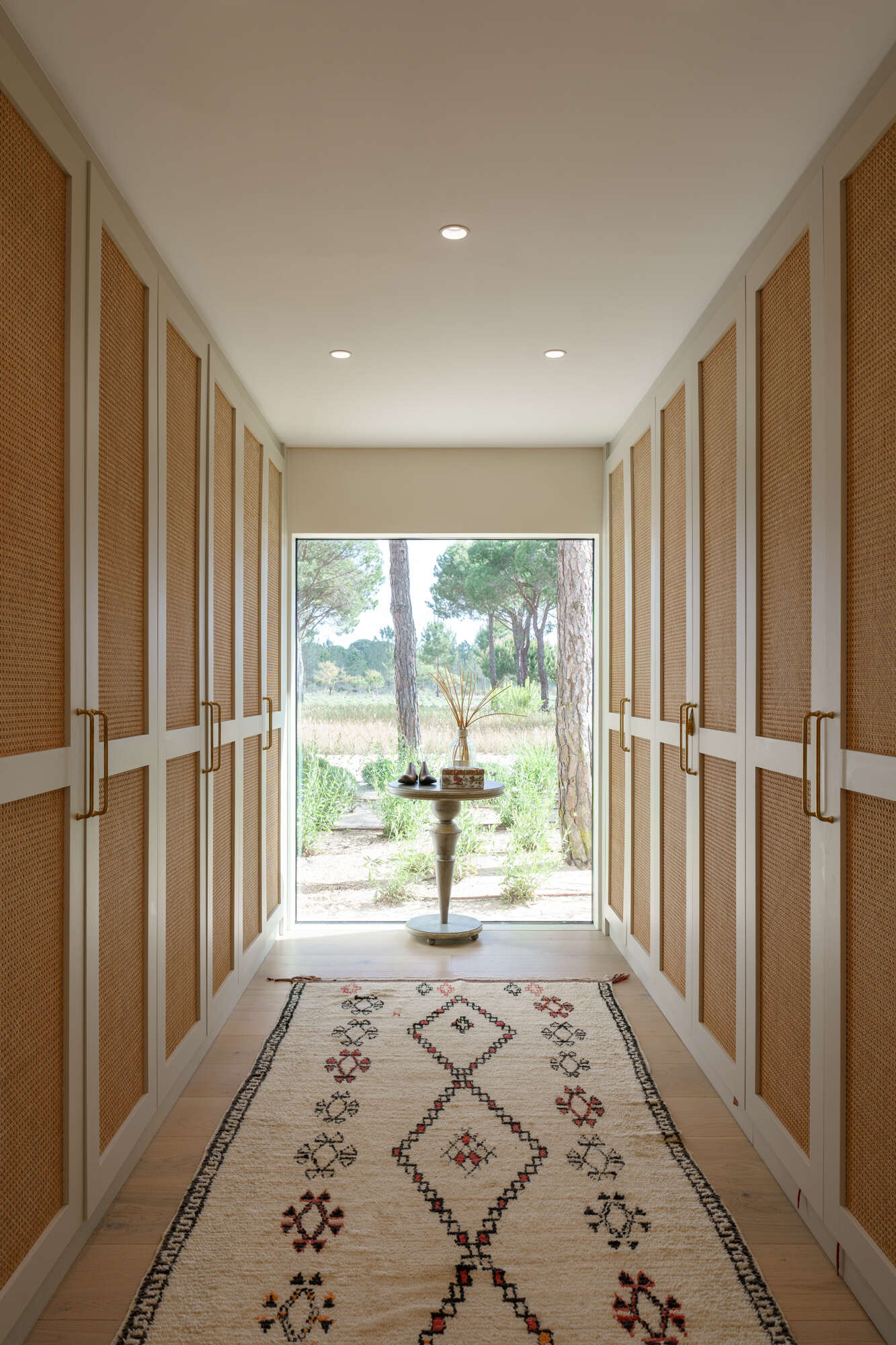 Warm timber details and minimalist finishes define this elegant walk-in closet inside the master suite of Casa na Comporta.