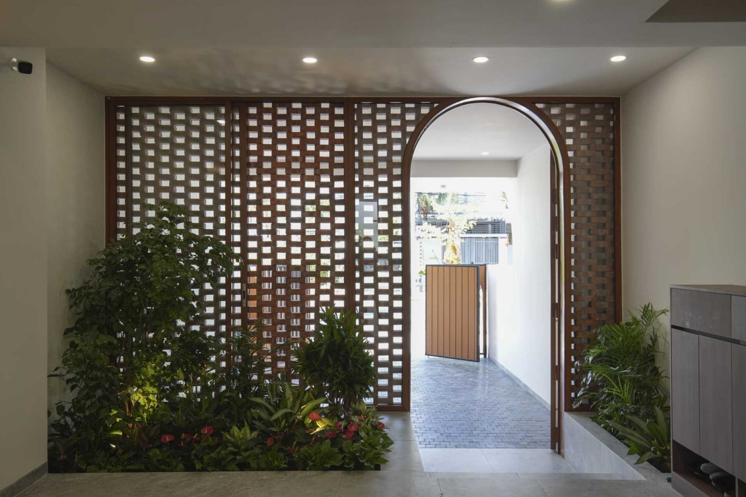 The ground floor combines built-in planters, a sitting area, and natural light to create an inviting entrance experience inside this narrow urban home.