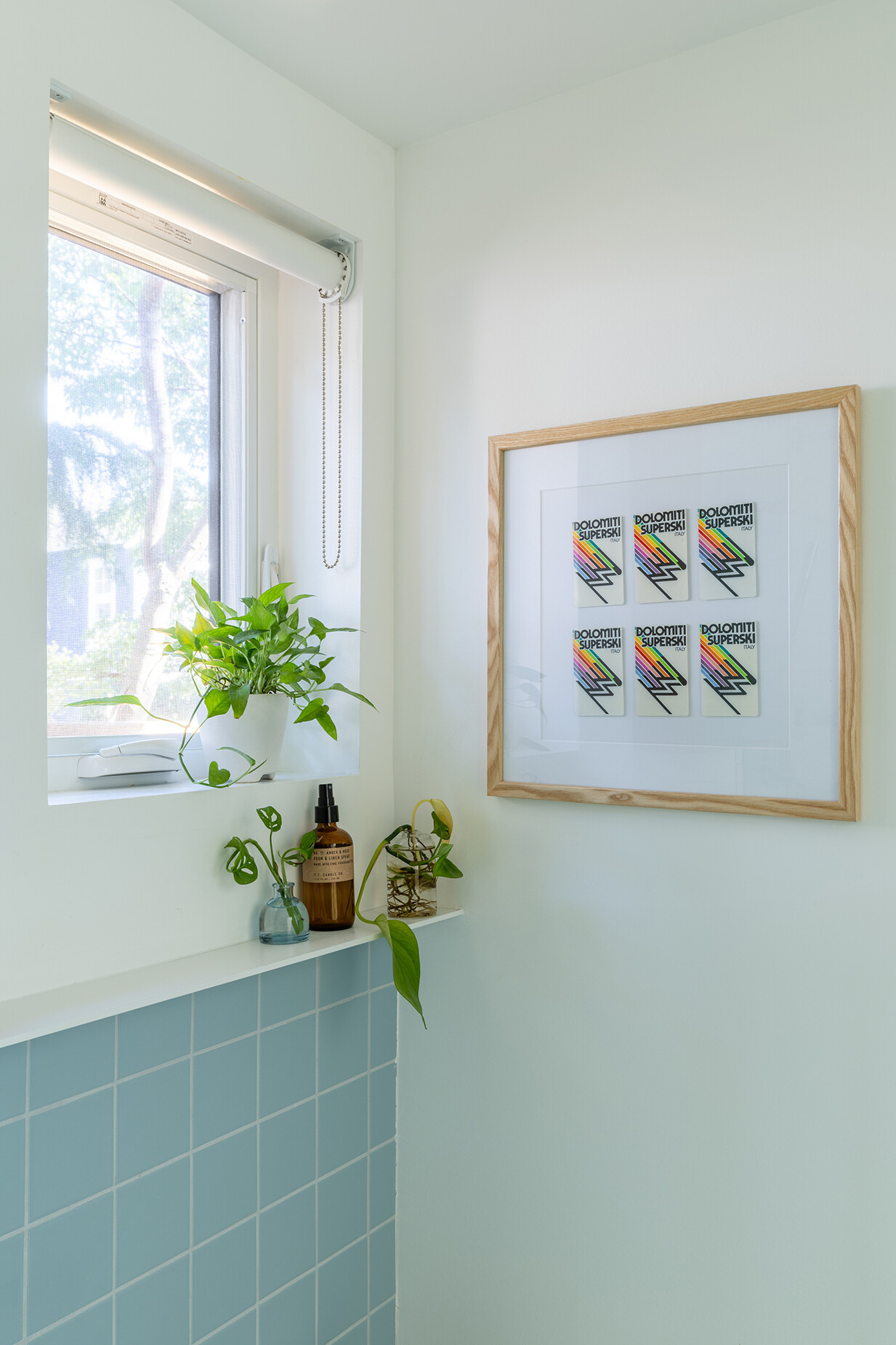 This compact bathroom combines blue tile, a concrete sink, floating shelves, and a barrier-free shower to create a bright and spacious feel.