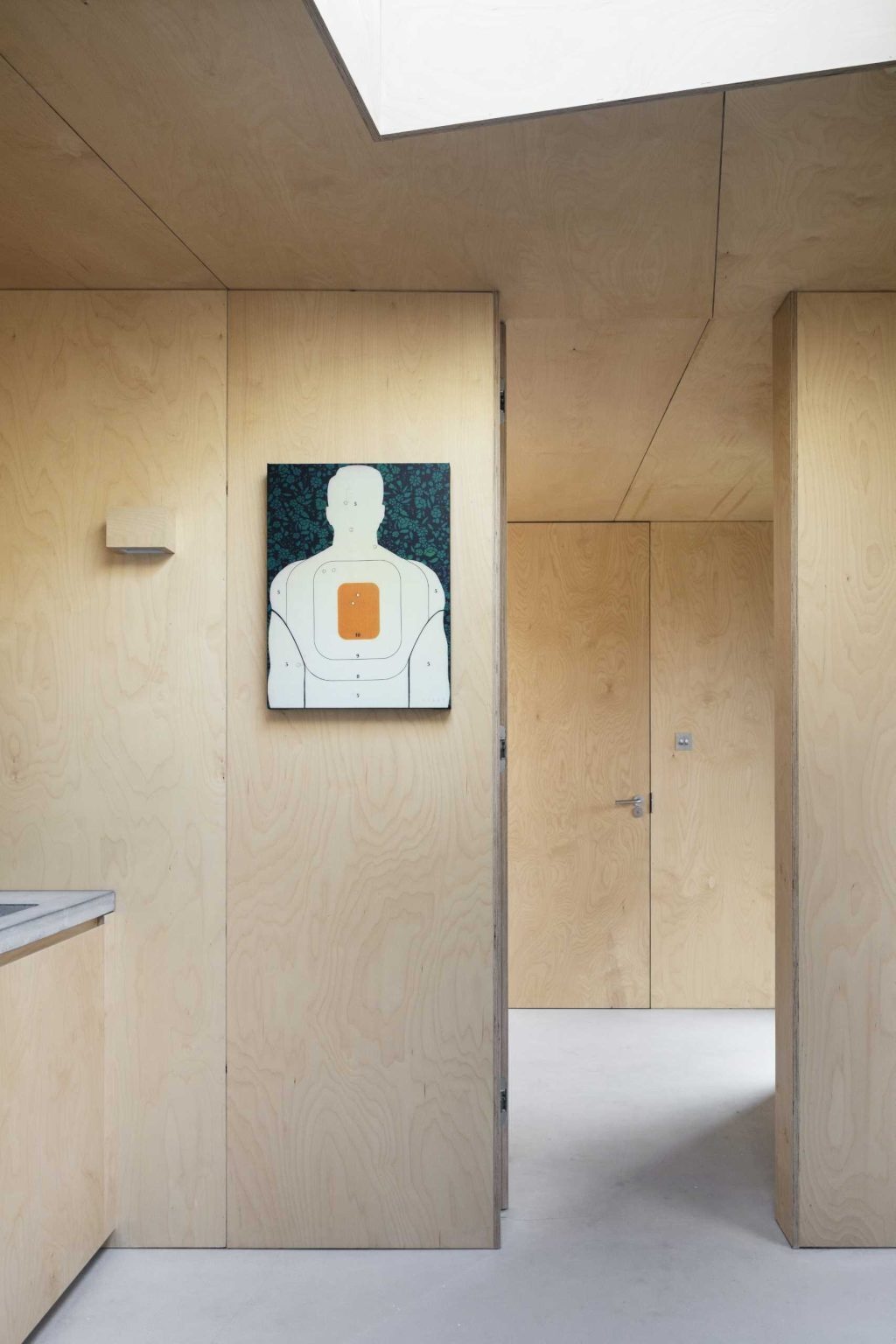 The guest suite continues the birch plywood palette and includes an open closet area and private bathroom.