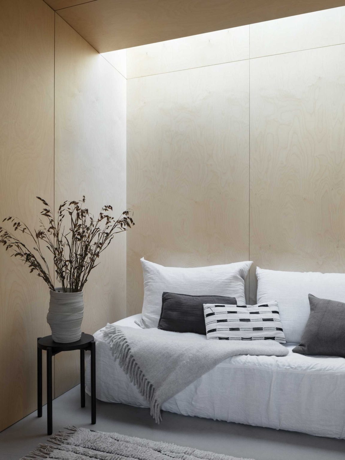 The guest suite continues the birch plywood palette and includes an open closet area and private bathroom.