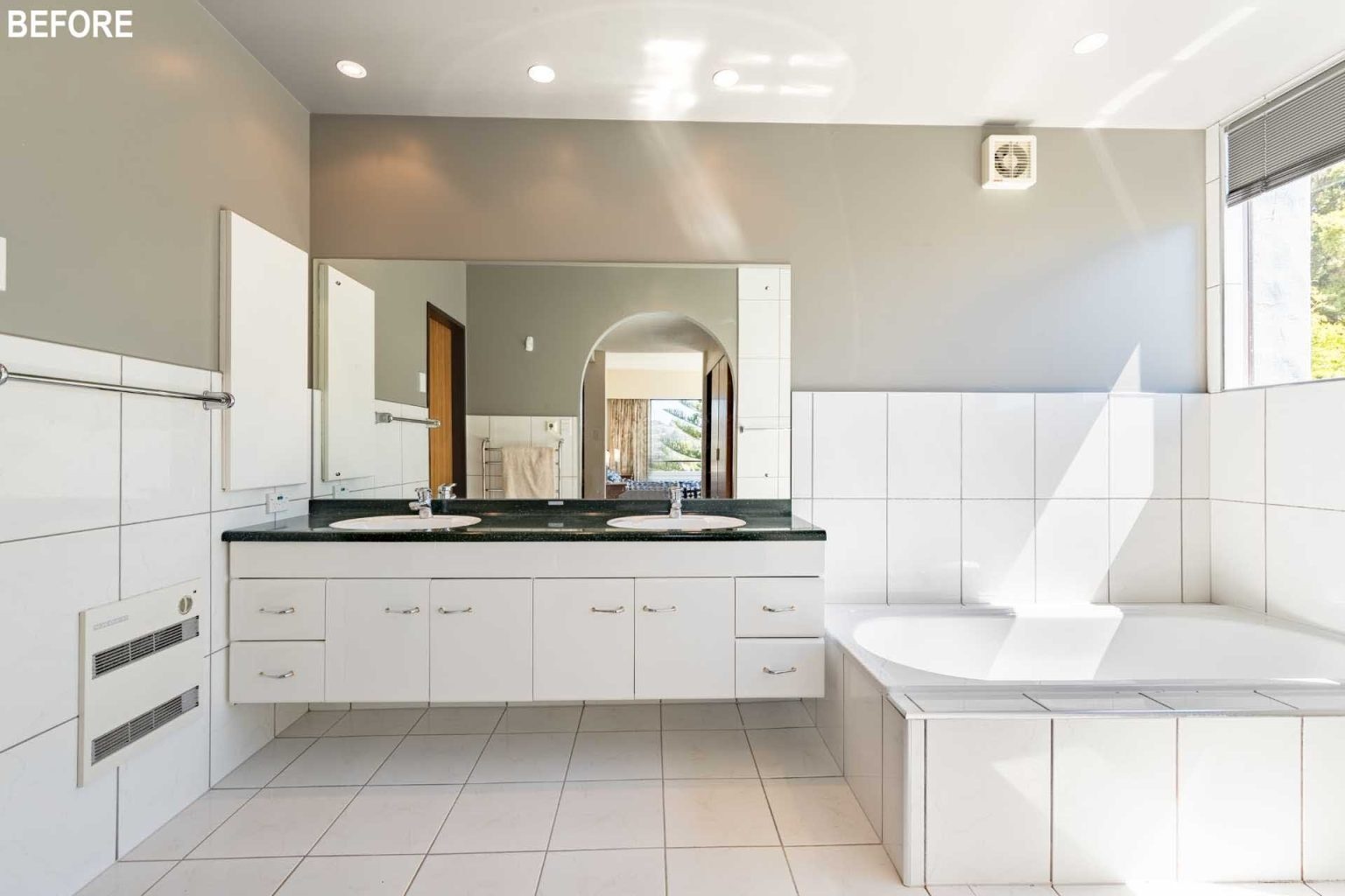 BEFORE - Large-format tiles, timber accents, and a freestanding bathtub transform this dated bathroom into a sleek and contemporary space.