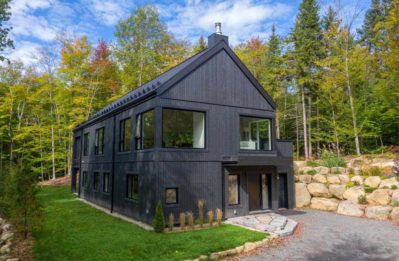 Clad in black metal and wood, the house embraces a simple architectural form while taking full advantage of its elevated position above Lac Marois. The design is intentionally understated from a distance, but as you move through the spaces, a series of warm, light-filled interiors begin to unfold.