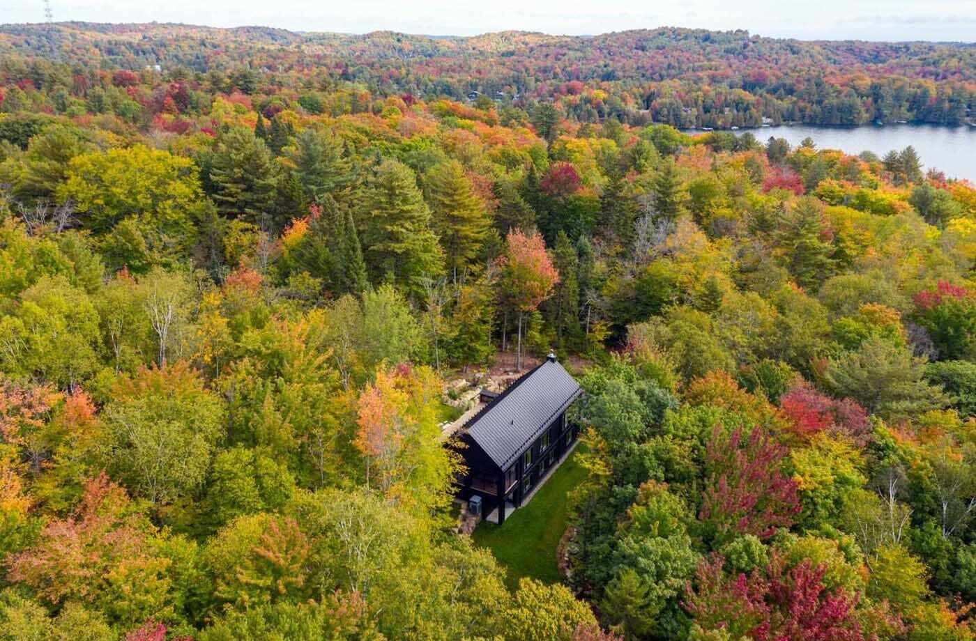 Clad in black metal and wood, the house embraces a simple architectural form while taking full advantage of its elevated position above Lac Marois. The design is intentionally understated from a distance, but as you move through the spaces, a series of warm, light-filled interiors begin to unfold.