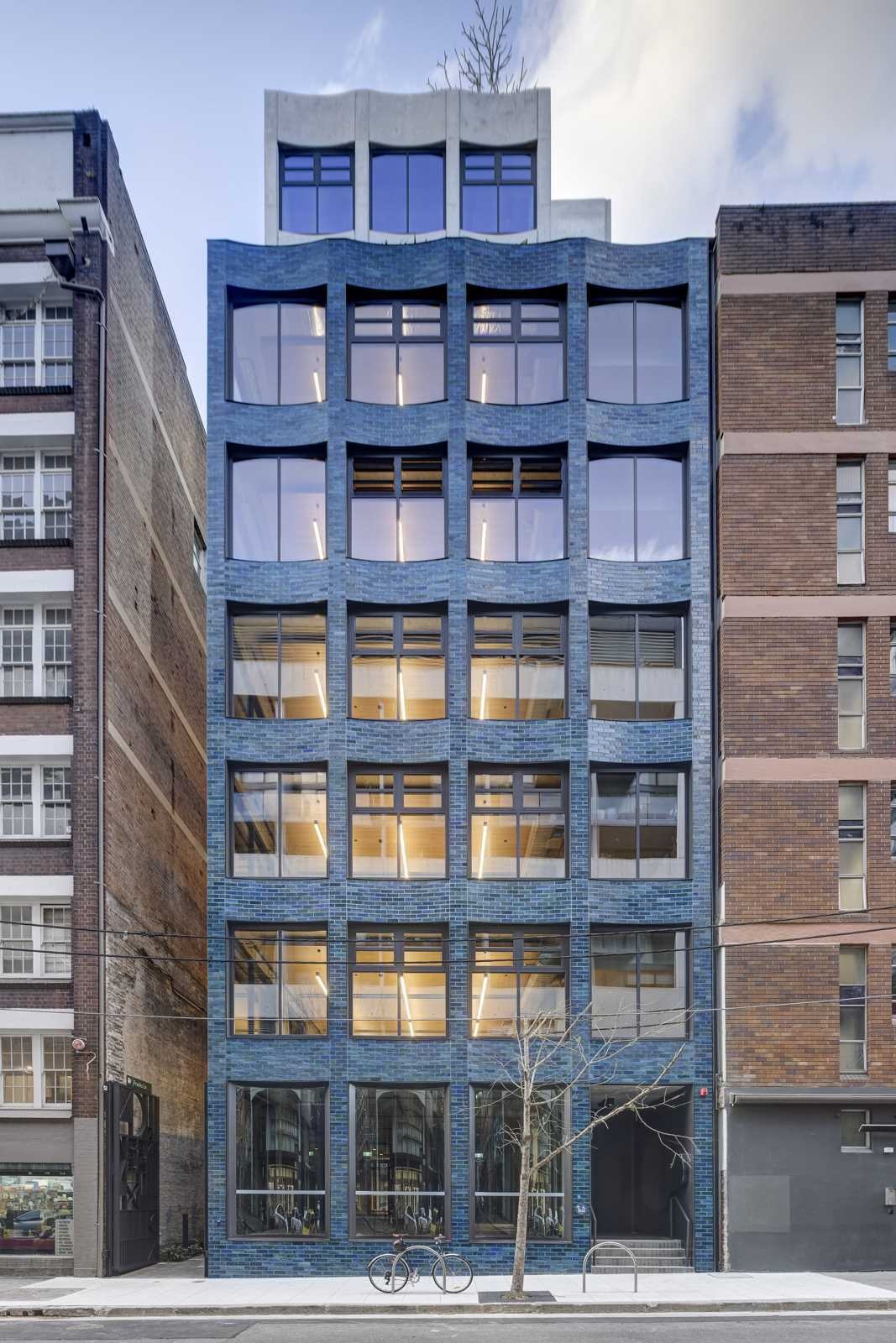 This aquamarine glazed-brick facade by SJB turns a Sydney office building into a sculptural landmark filled with texture, color, and architectural detail.