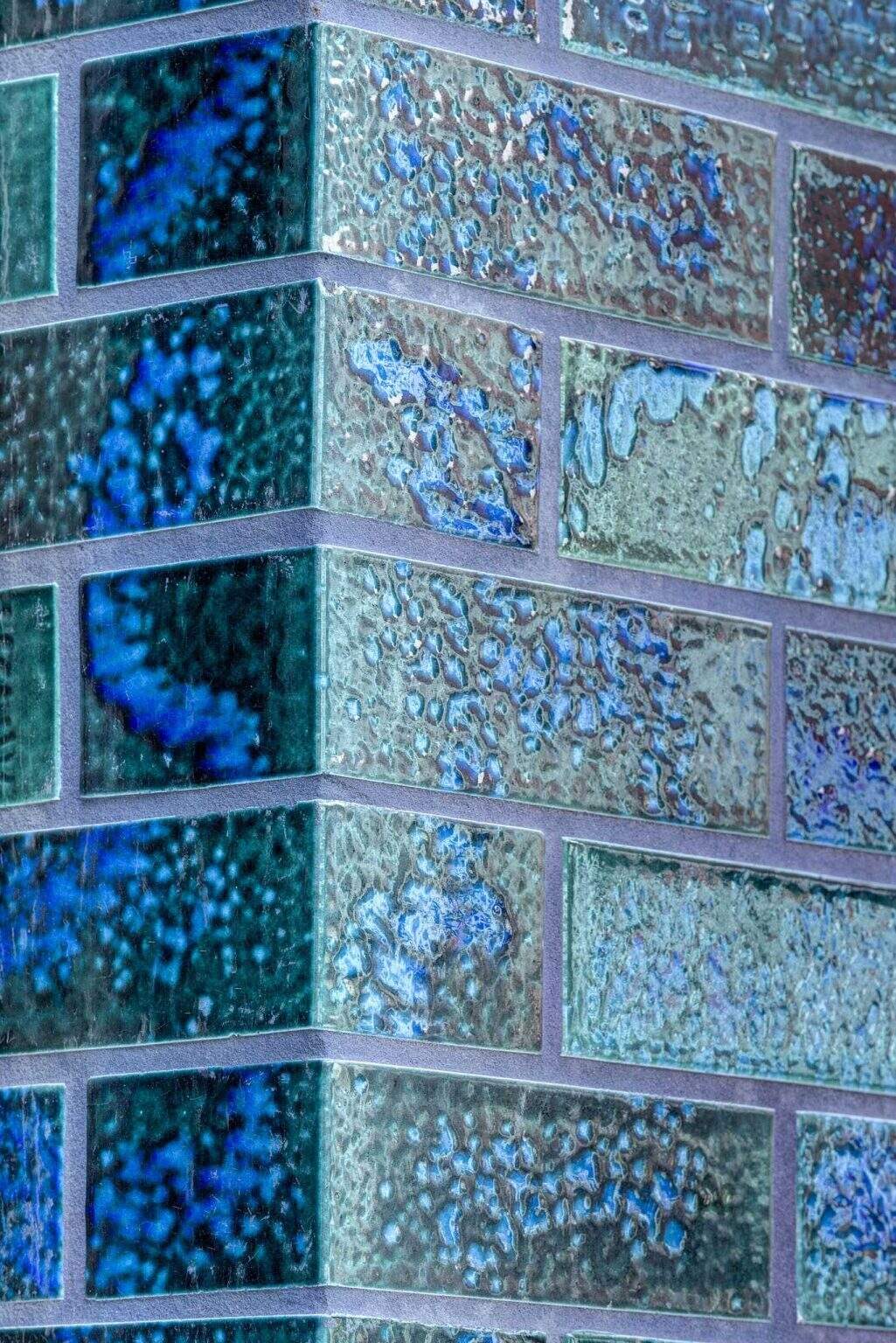 This aquamarine glazed-brick facade by SJB turns a Sydney office building into a sculptural landmark filled with texture, color, and architectural detail.