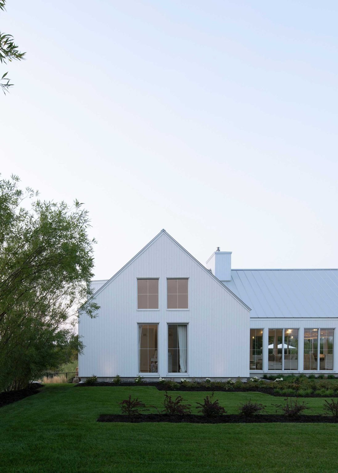 A generous setback, quiet surroundings, and a light monochrome exterior help this modern Quebec home make the most of its beautiful natural setting.