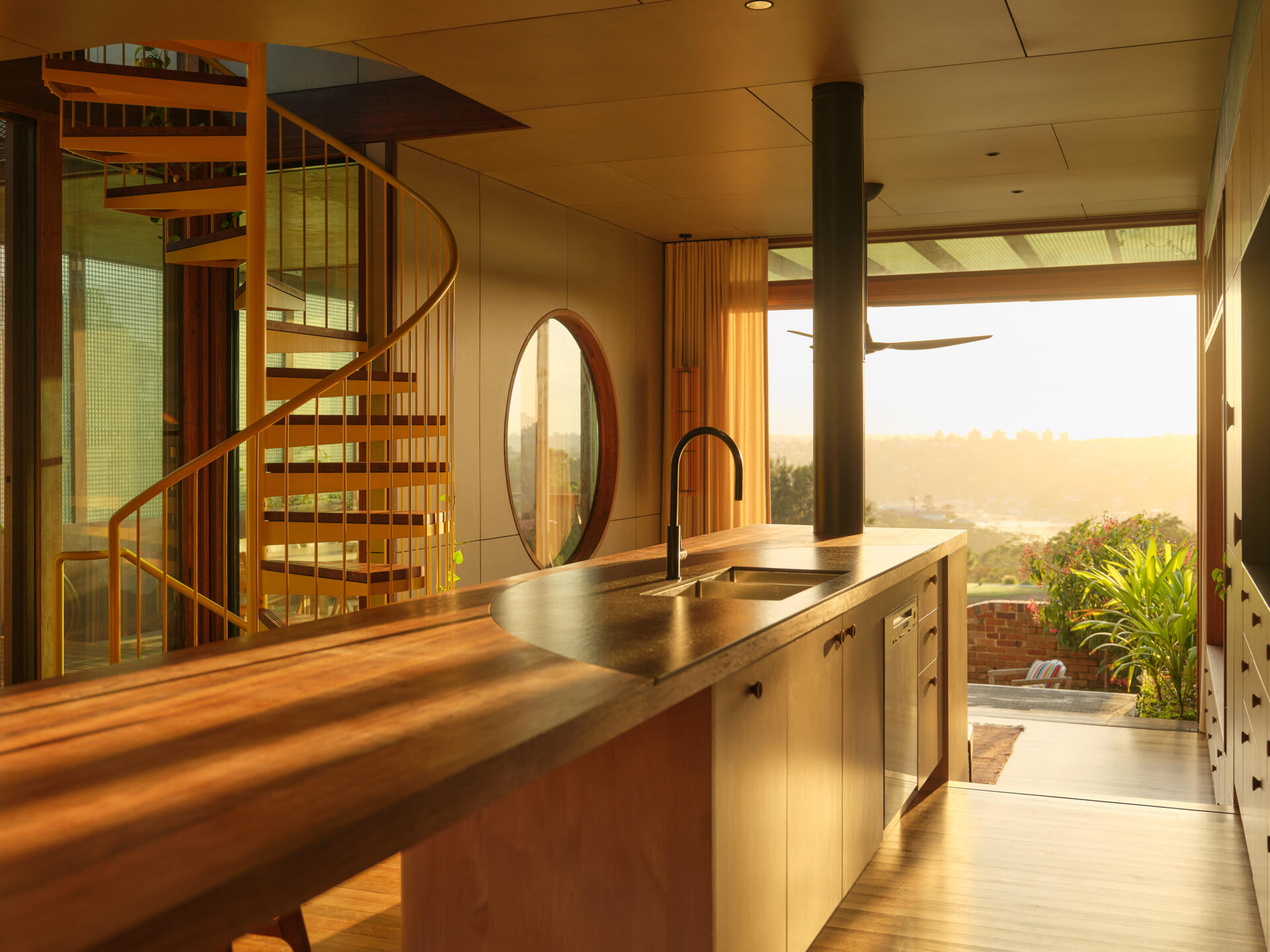 This contemporary kitchen combines a recycled hardwood island, walk-in pantry, harbour views, and custom timber detailing perfect for family gatherings.