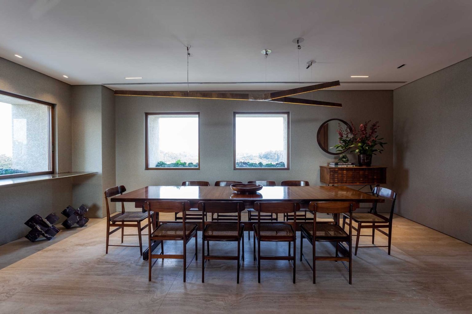 Brazilian design takes center stage in this elegant dining room featuring Sergio Rodrigues furniture, Roman Travertine marble flooring, and a sculptural statement light.