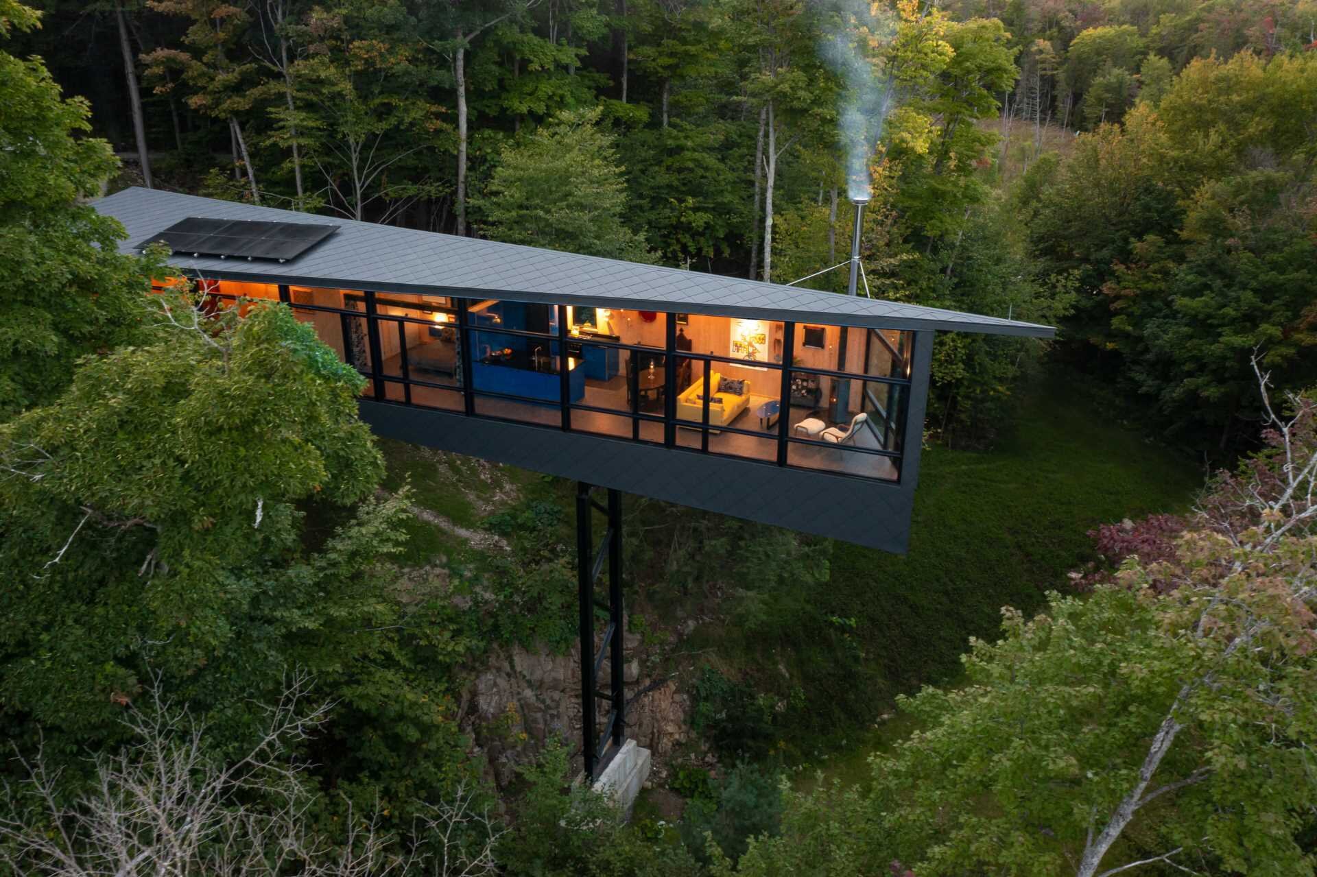 A steel mast and minimal foundation give this modern cabin its floating appearance while helping preserve the forest below.