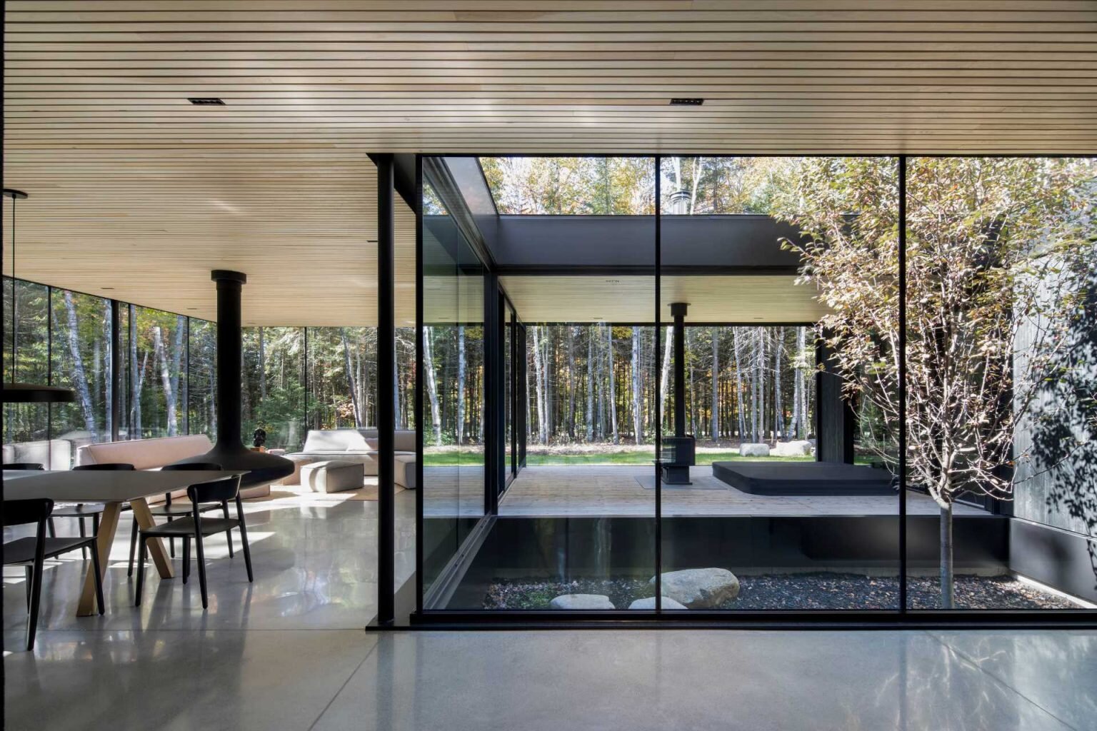 The entryway blends concrete floors with a wood ceiling, offering a striking material contrast that introduces the home’s architectural language.