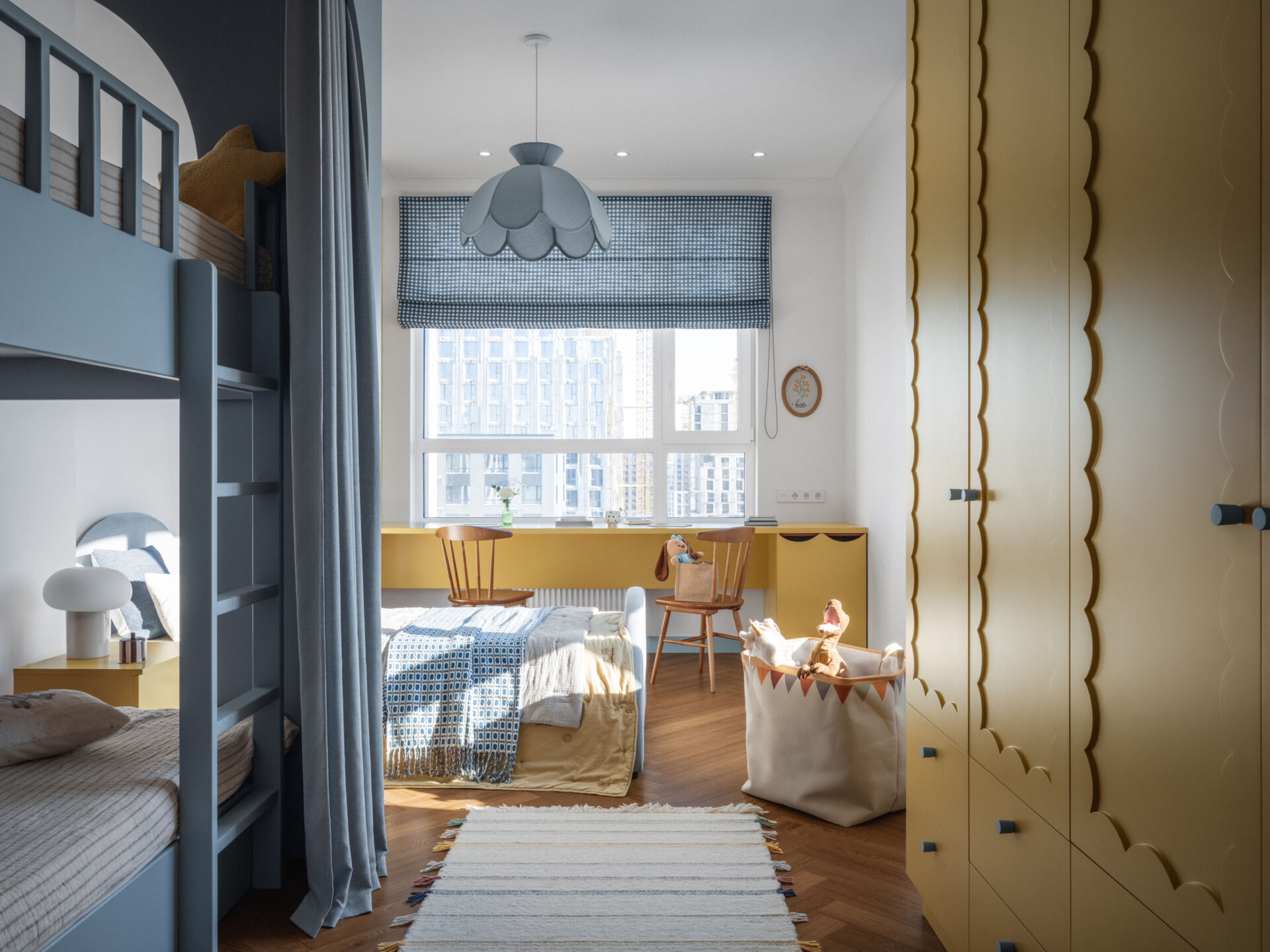 In this children's bedroom for three, colorful yellow cabinets with fun detailing line the wall and at the same time complement the built-in desk underneath the window. Nearby a single bed and a bunk bed provides plenty of space for the children to each have their own area.