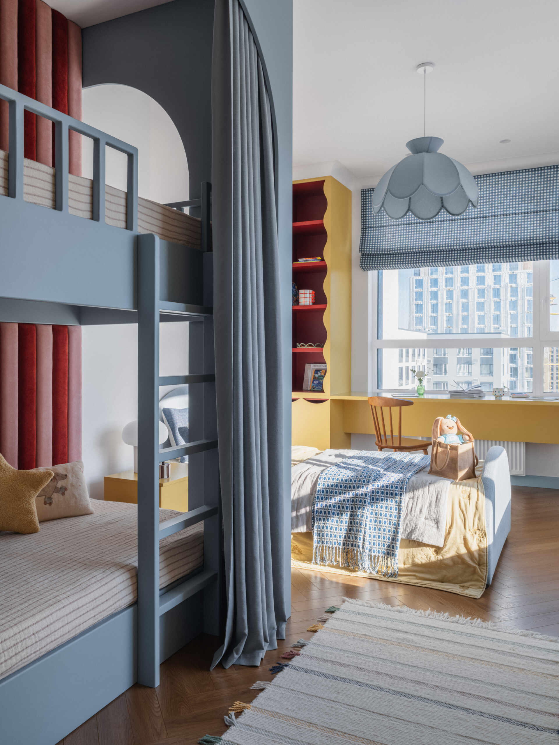 In this children's bedroom for three, colorful yellow cabinets with fun detailing line the wall and at the same time complement the built-in desk underneath the window. Nearby a single bed and a bunk bed provides plenty of space for the children to each have their own area.