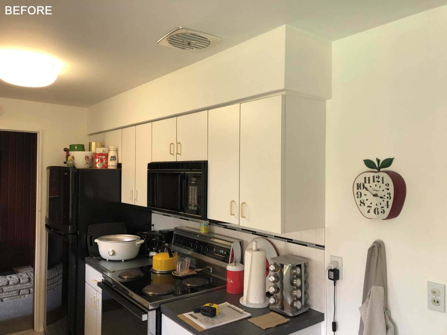 BEFORE - This open-concept kitchen replaces a once closed-off layout with white countertops, wood cabinetry, a window-side bar area, and seamless connections to the dining and living spaces.