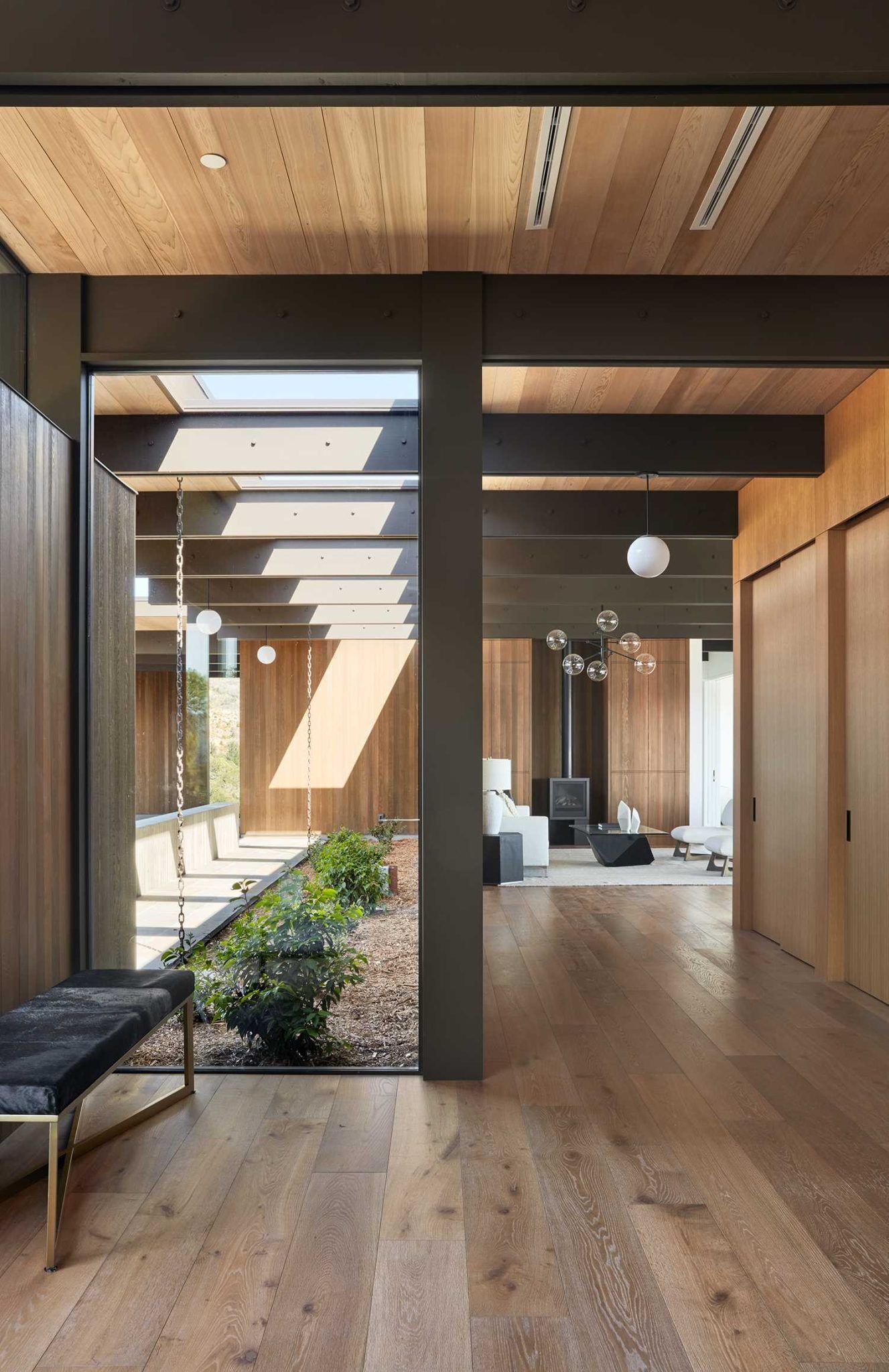 Warm wood finishes, hidden doors, and a sculptural chandelier create an inviting first impression inside this California home.