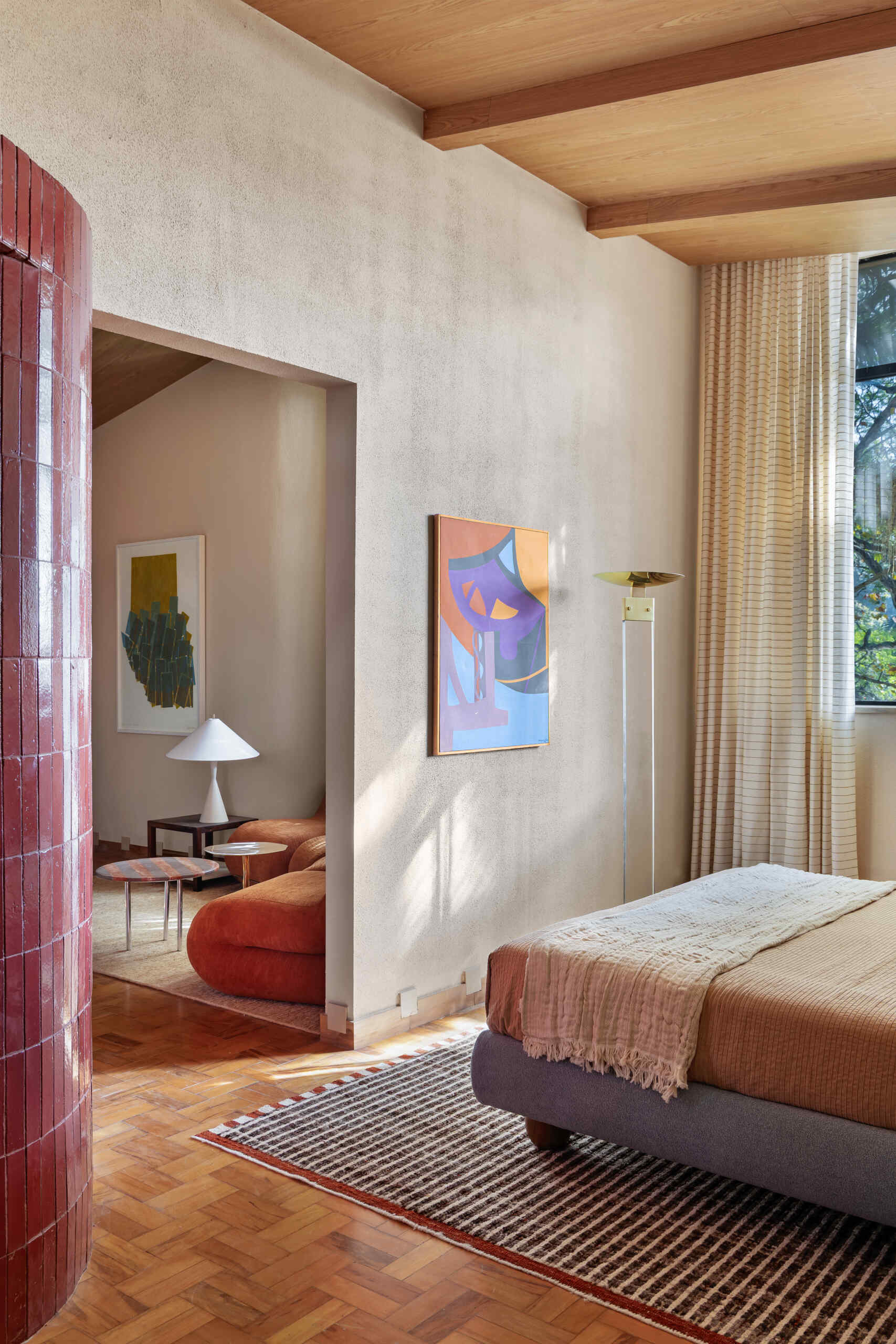 A blue upholstered headboard, slatted timber detailing, vintage lighting, and exposed beams create a serene bedroom full of character.