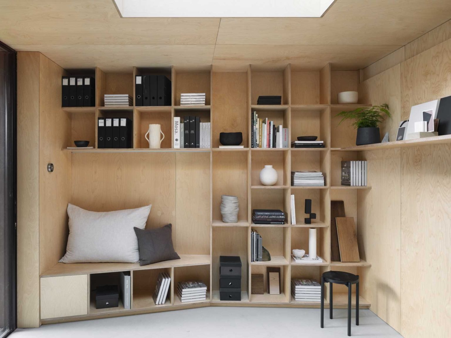 A full wall of bookshelves with an integrated seating nook turns storage into a functional design feature.