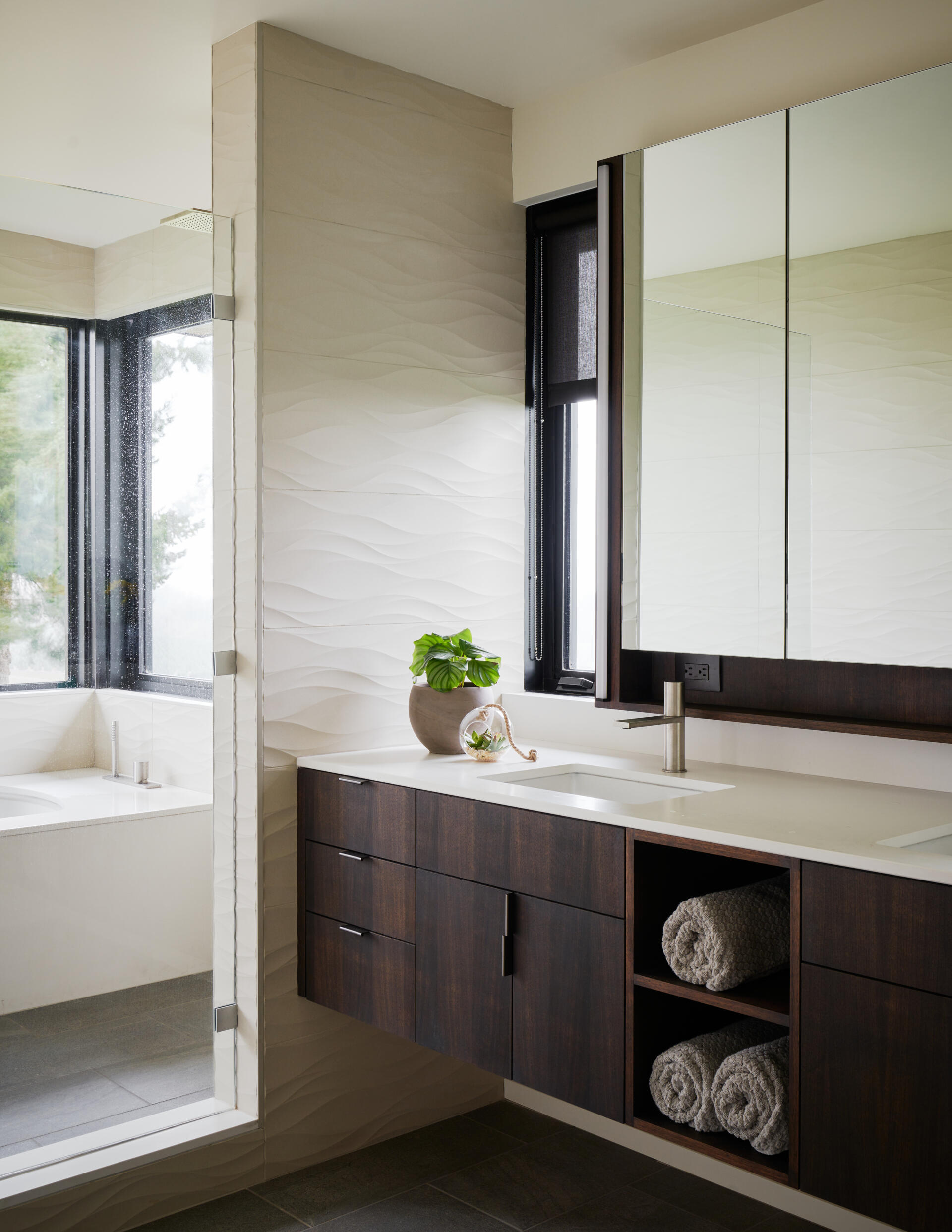 A modern bathroom with a dark wood vanity and a wetroom that includes a built-in bathtub.