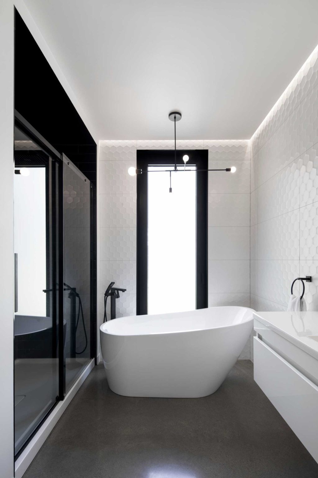 A bathroom features full-height tiled walls, a freestanding bathtub, and a walk-in shower, adding texture and depth.
