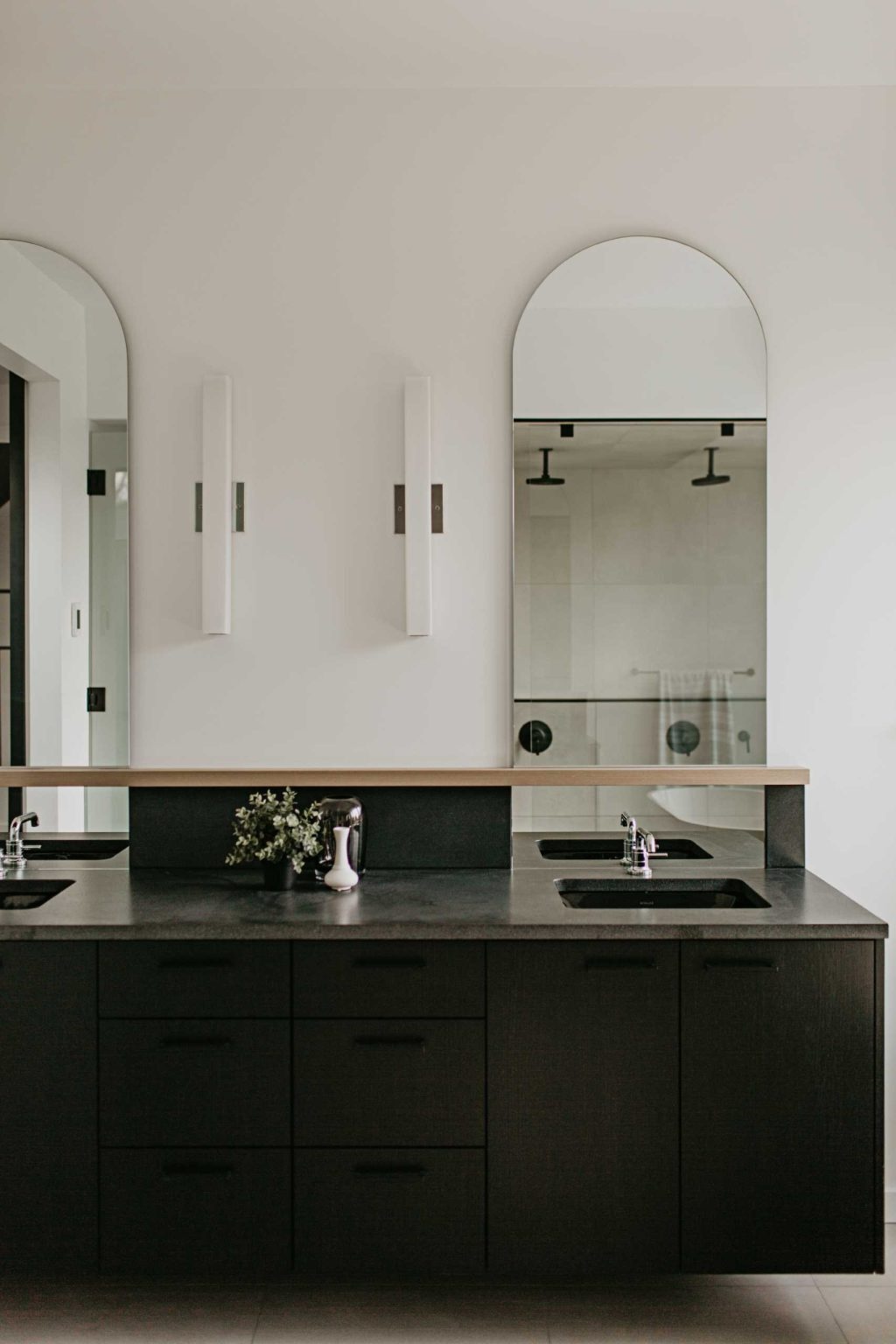 Arched mirrors, black vanities, terrazzo tile, and a freestanding tub create a bathroom full of elegant modern inspiration.