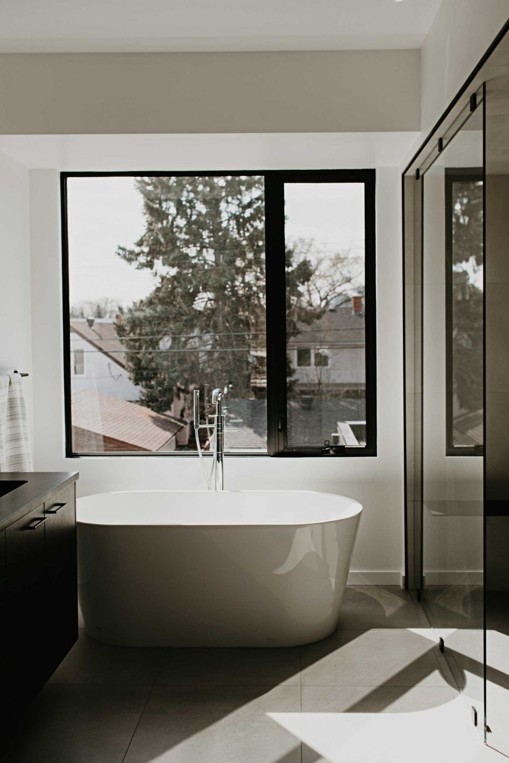 Arched mirrors, black vanities, terrazzo tile, and a freestanding tub create a bathroom full of elegant modern inspiration.