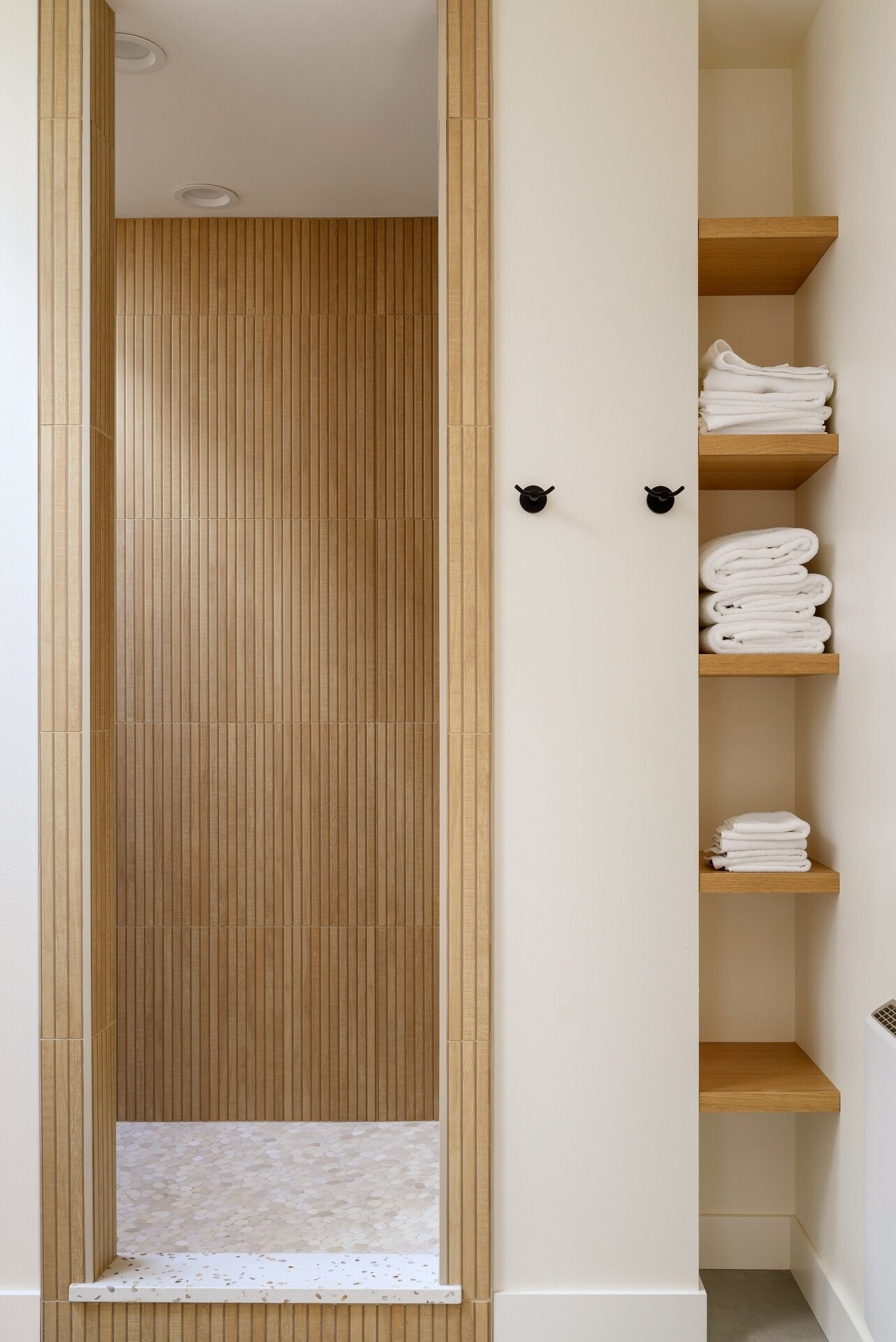 Discover a bright modern bathroom featuring warm timber cabinetry, skylights, black accents, and a beautifully cohesive material palette.