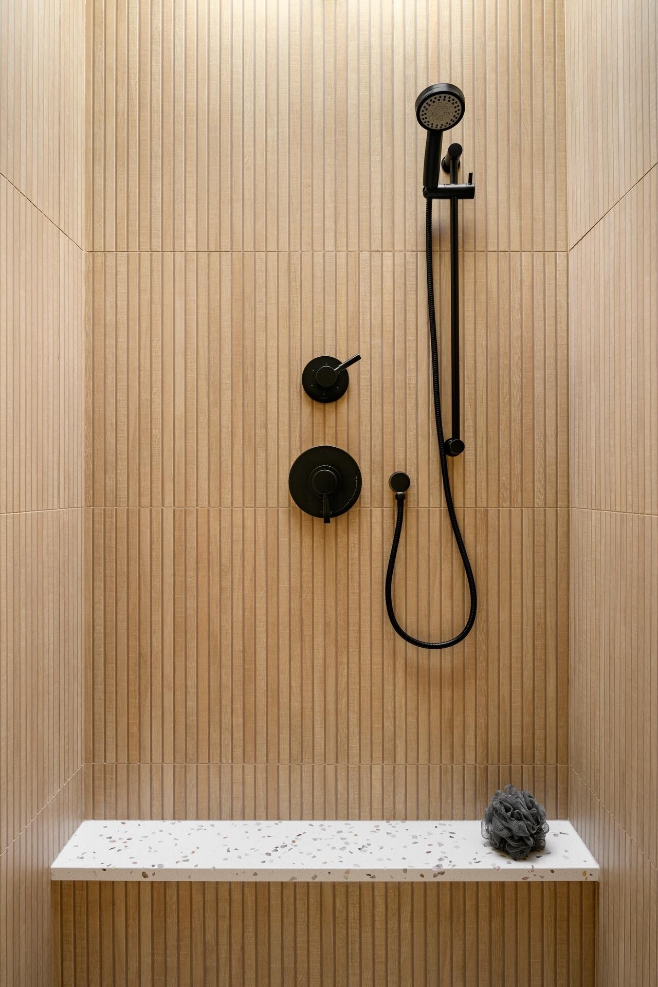 Discover a bright modern bathroom featuring warm timber cabinetry, skylights, black accents, and a beautifully cohesive material palette.