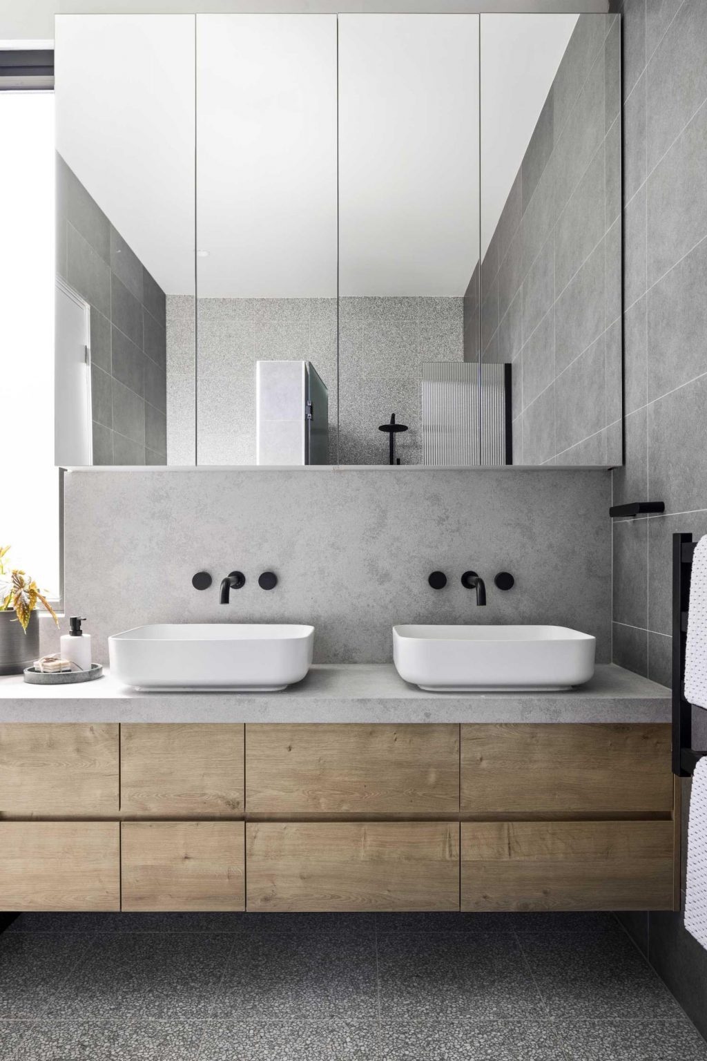 Terrazzo flooring, a timber vanity, and black fixtures come together to create a bathroom full of texture and contemporary style.