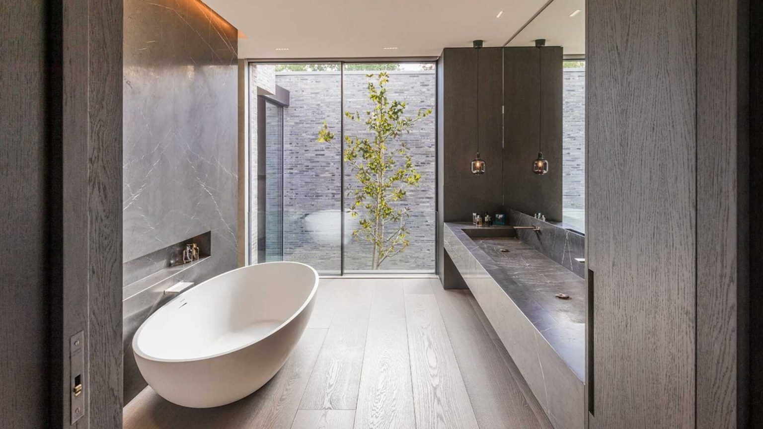 A freestanding bathtub, recessed shelving, and views of textured brickwork define this elegant contemporary bathroom.