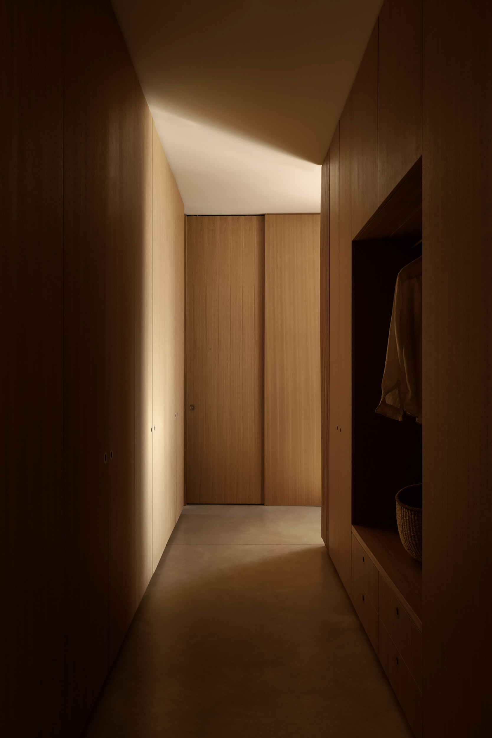 A dressing area continues the home's restrained approach, providing generous storage while maintaining clean lines and minimal visual clutter.