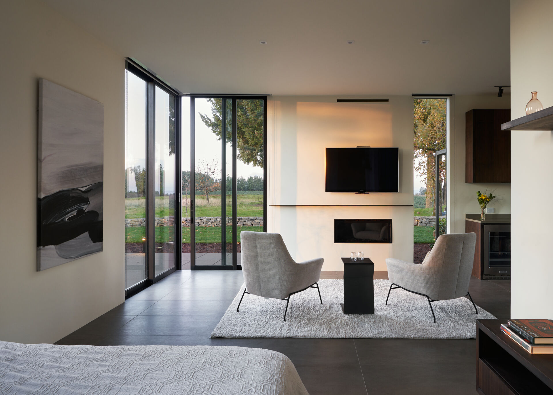 A modern guest suite with fireplace and full height glass walls that open at the corner.