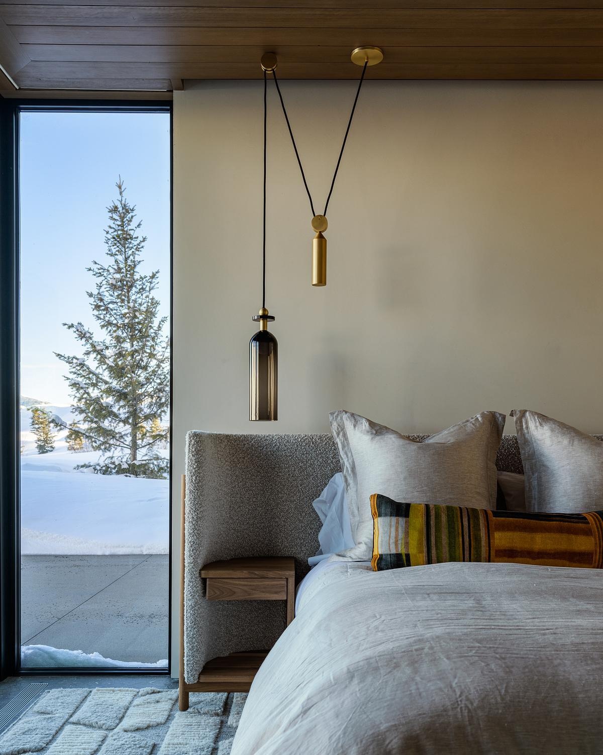 Warm timber ceilings, exposed beams, oversized windows, and layered textures give these modern bedrooms a cozy yet sophisticated feel, with mountain views becoming part of the design.