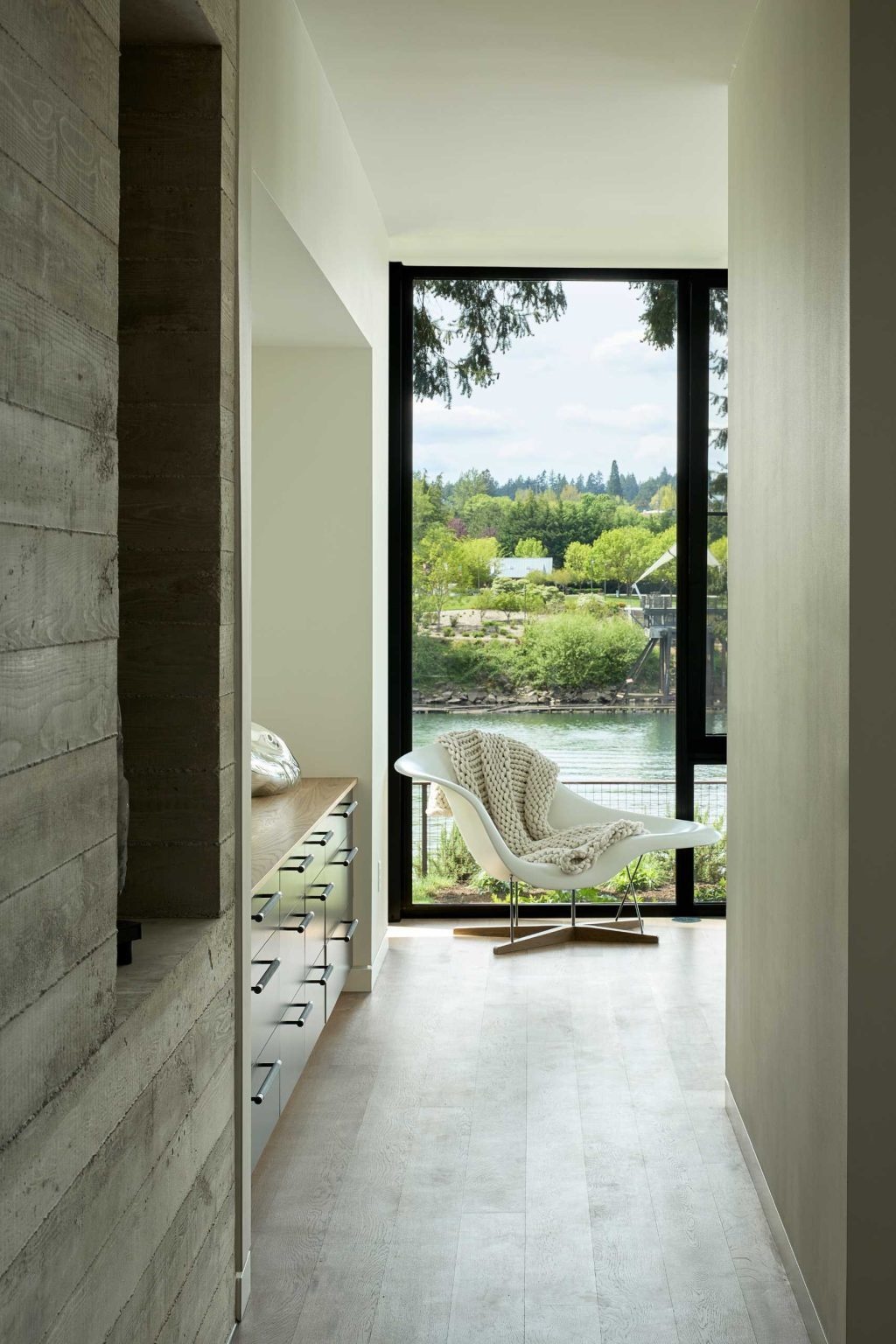 Floor-to-ceiling windows frame stunning river views in this modern bedroom, creating a bright and peaceful space.