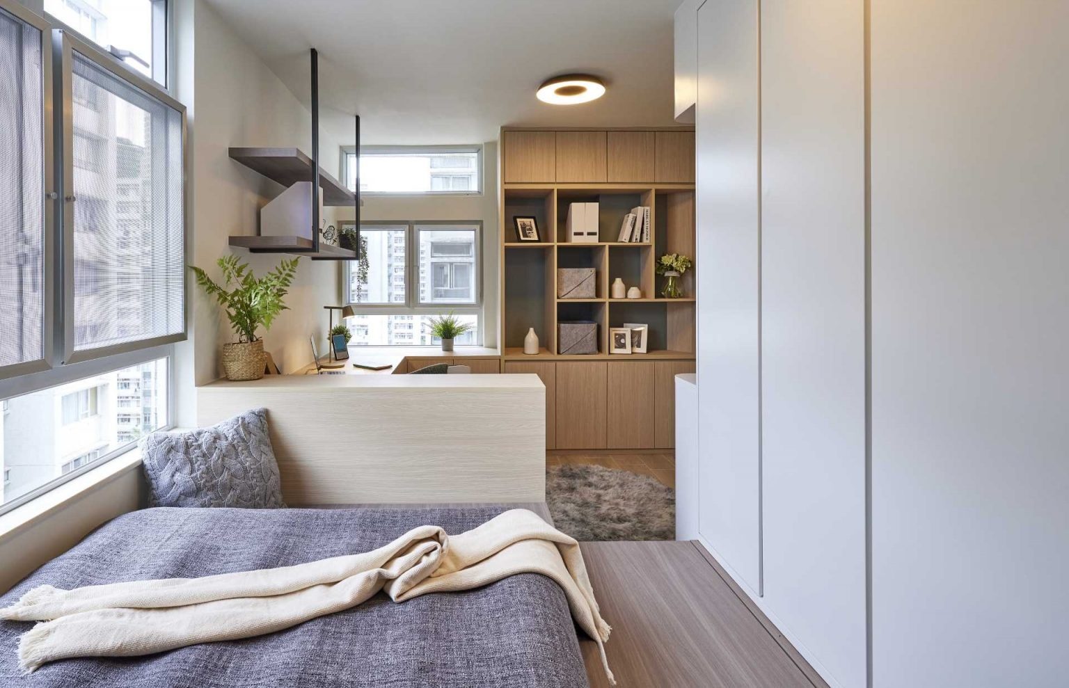 Hidden storage, a green leather headboard, and textured walls make this compact bedroom feel stylish and practical. Perfect inspiration for small-space living.